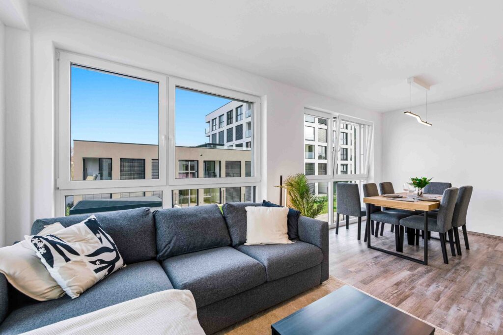 Living room with sofa and dining area, bright windows
