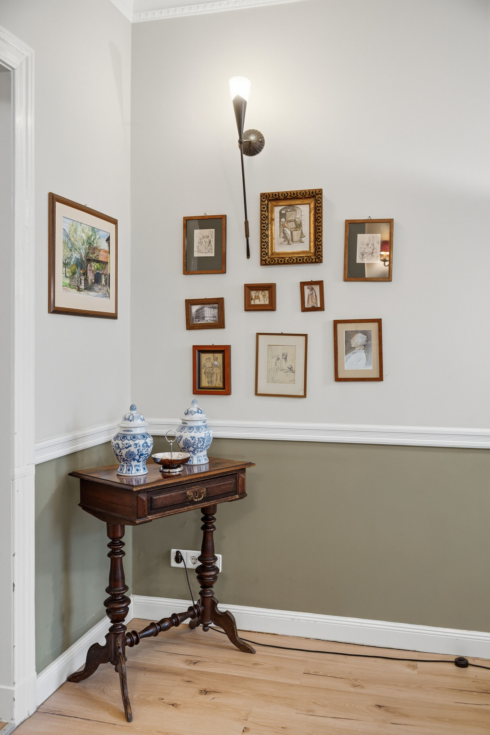 Gallery wall of framed art above antique side table