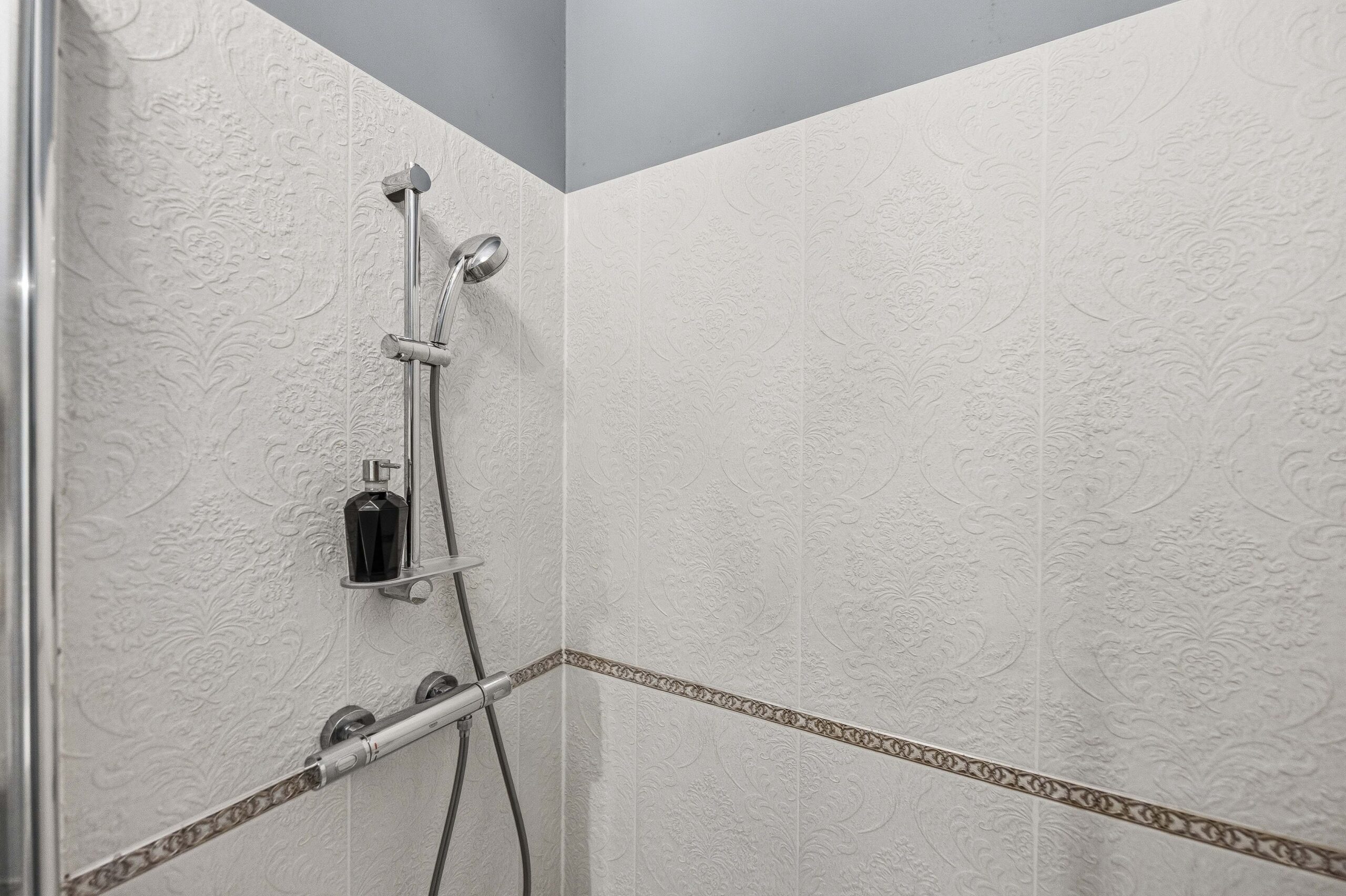 Walk-in shower with tiled walls and handheld head