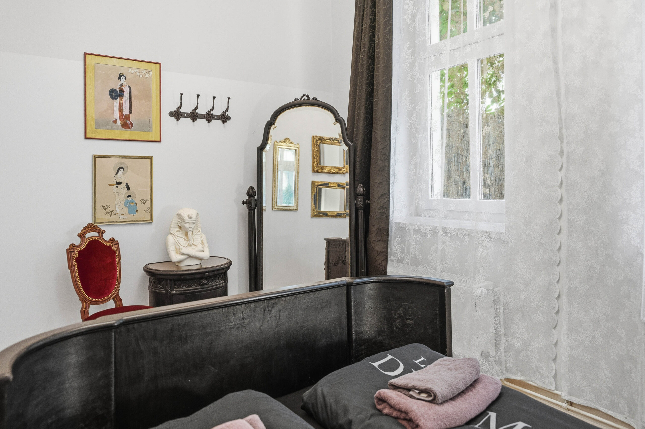 Bed corner with vintage mirror and framed art