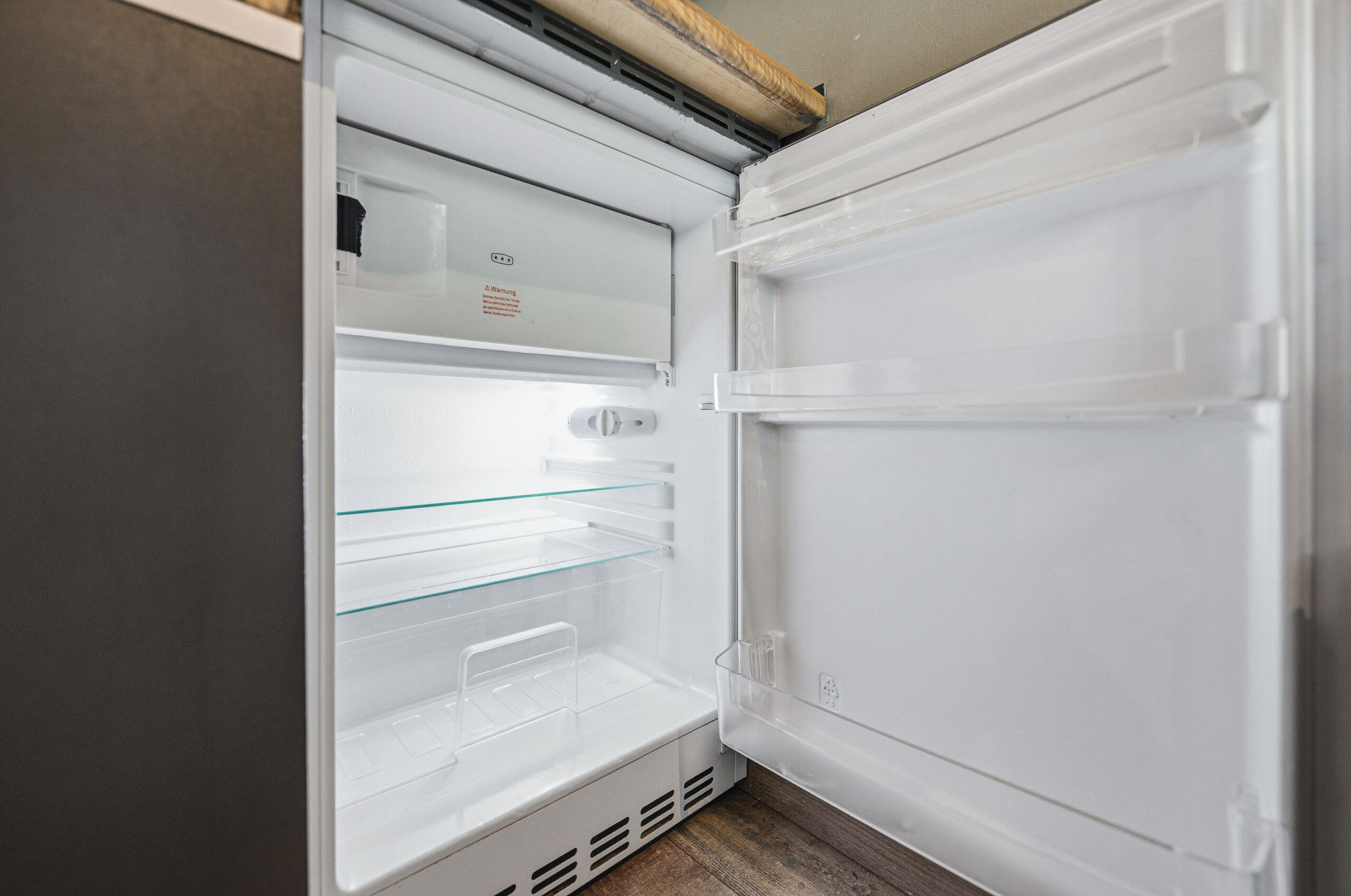 Empty open refrigerator with white interior shelves