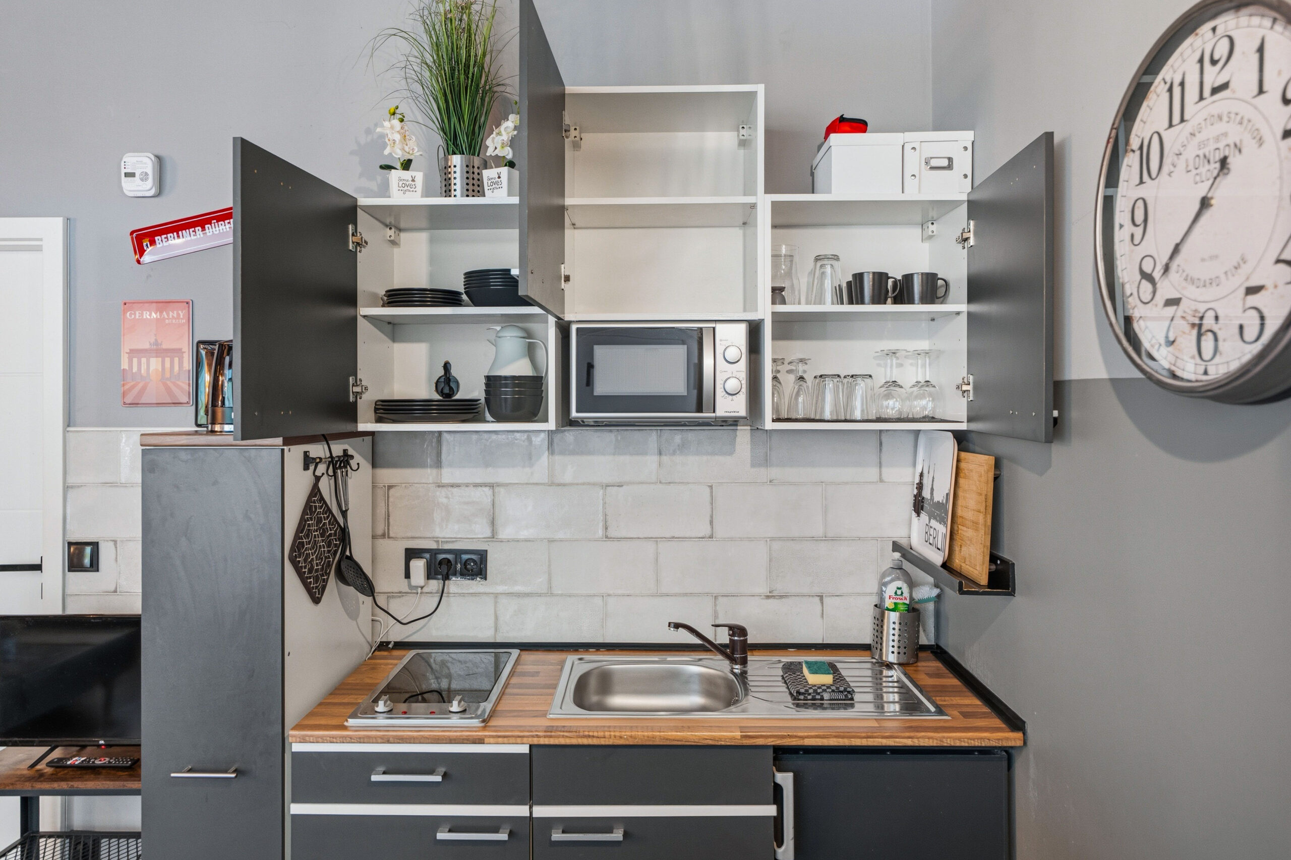 Kitchen cabinets open showing dishes and microwave