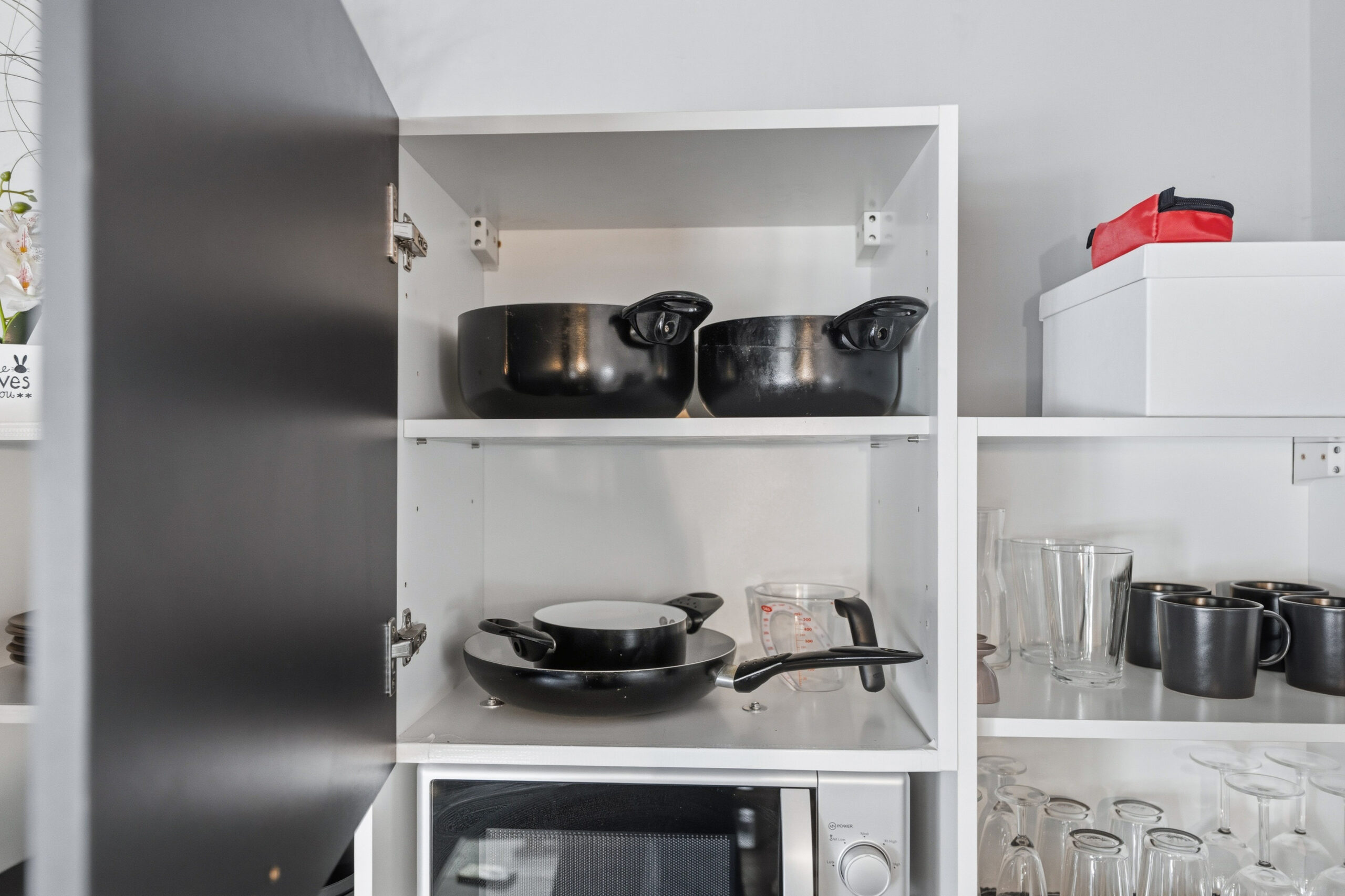 Open cabinet with pots, plates and microwave