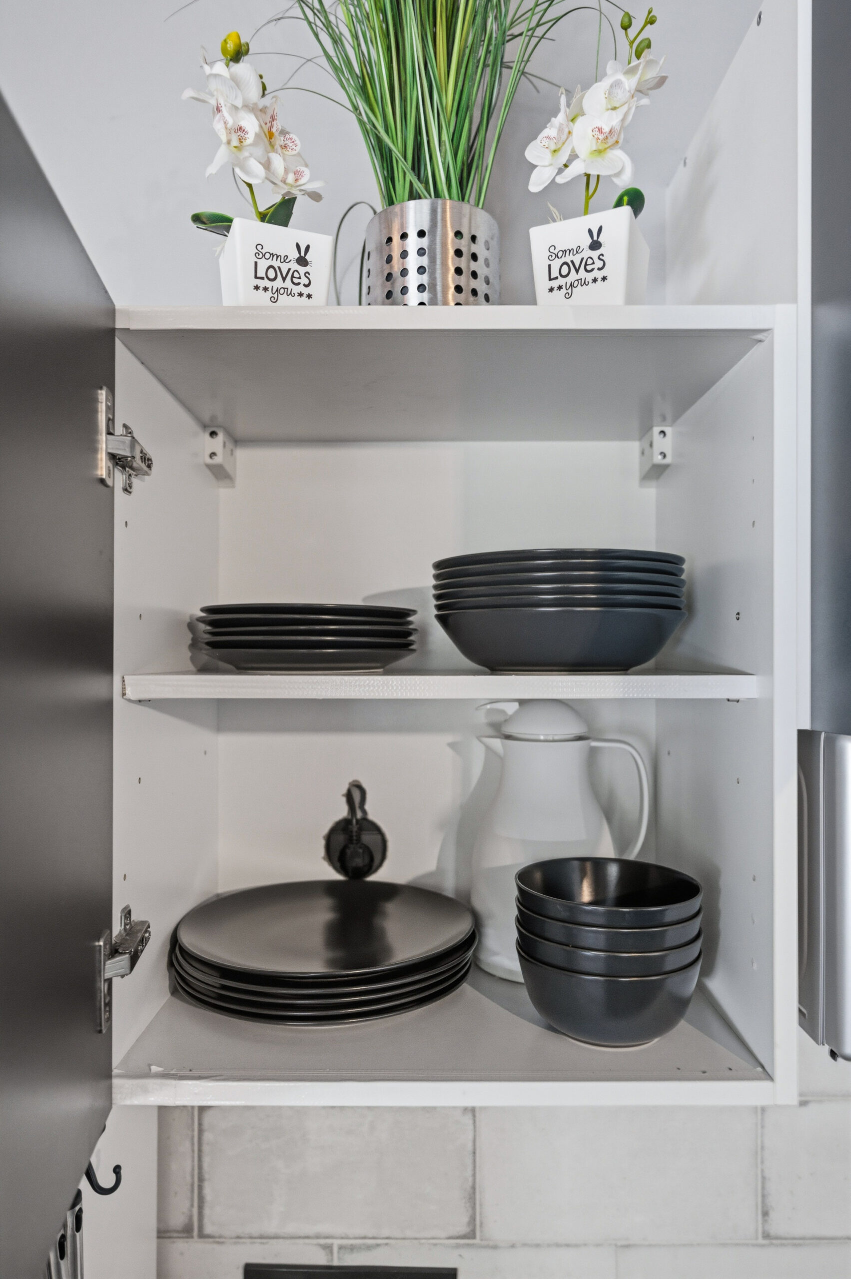 Open shelf with black plates, bowls and pitcher