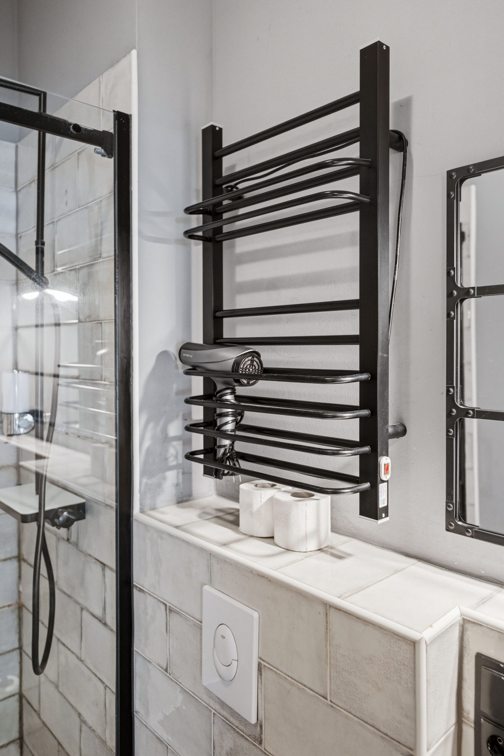 Black towel heater above tiled bathroom wall