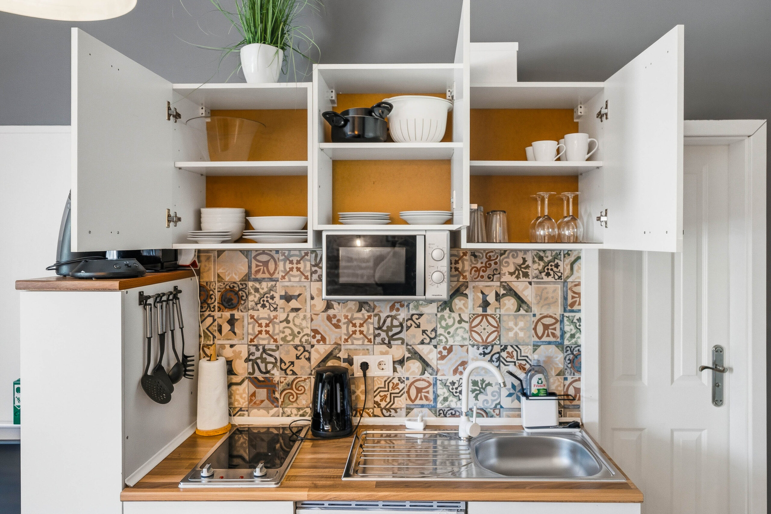 Kitchen cabinets open revealing dishes and microwave