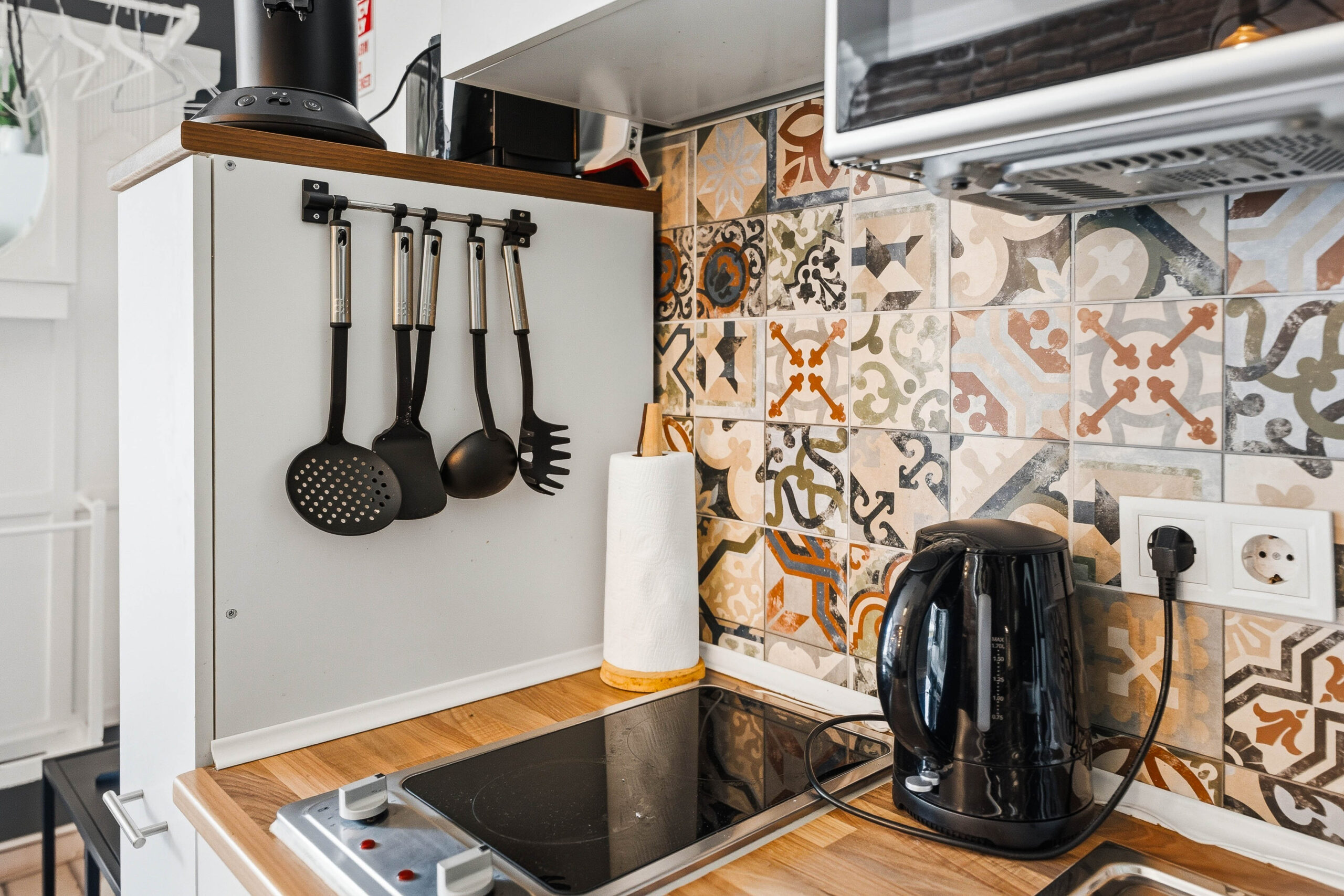 Stovetop with hanging utensils and patterned tile backsplash