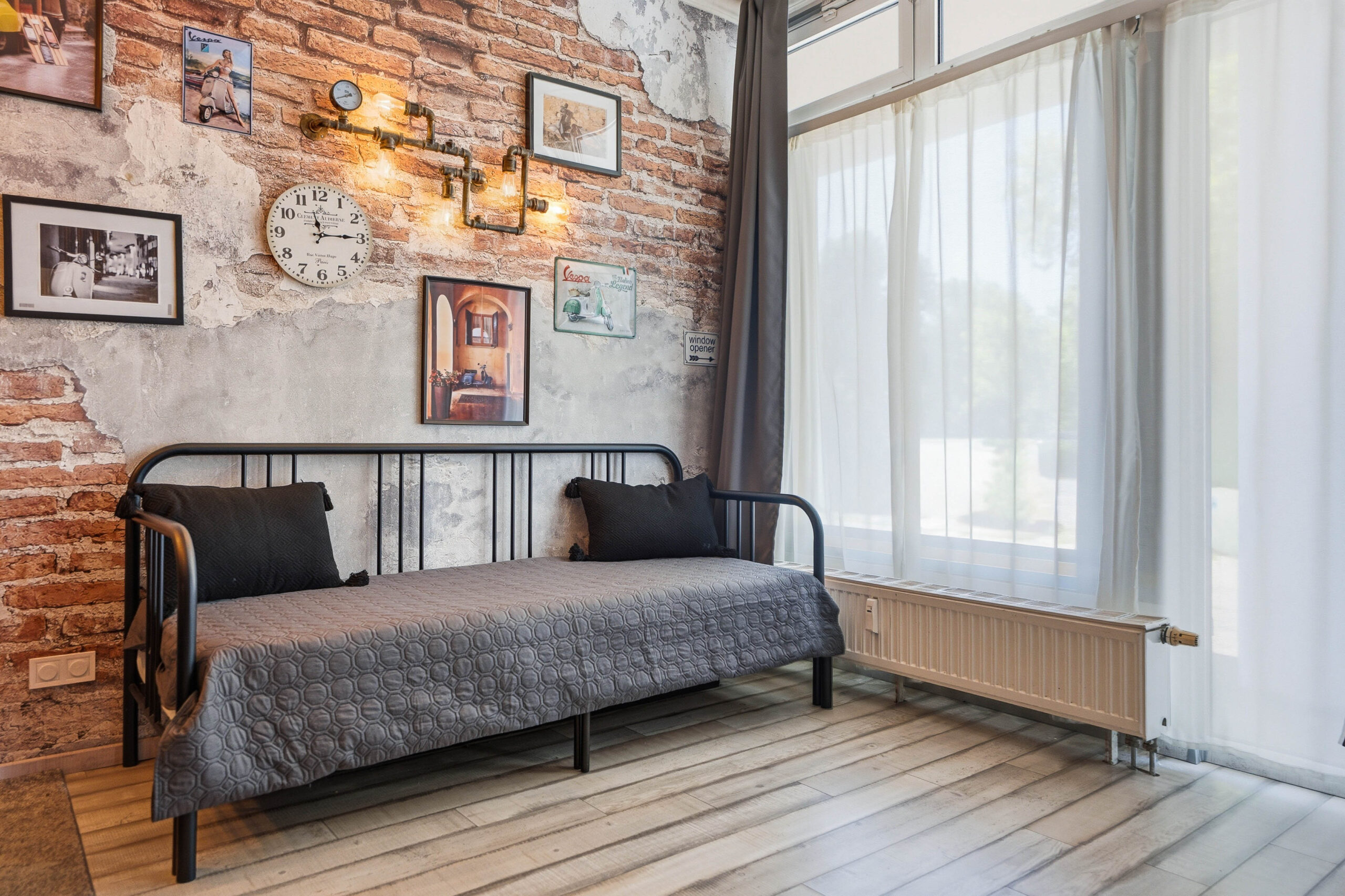 Daybed against brick wall with wall-mounted clock and frames