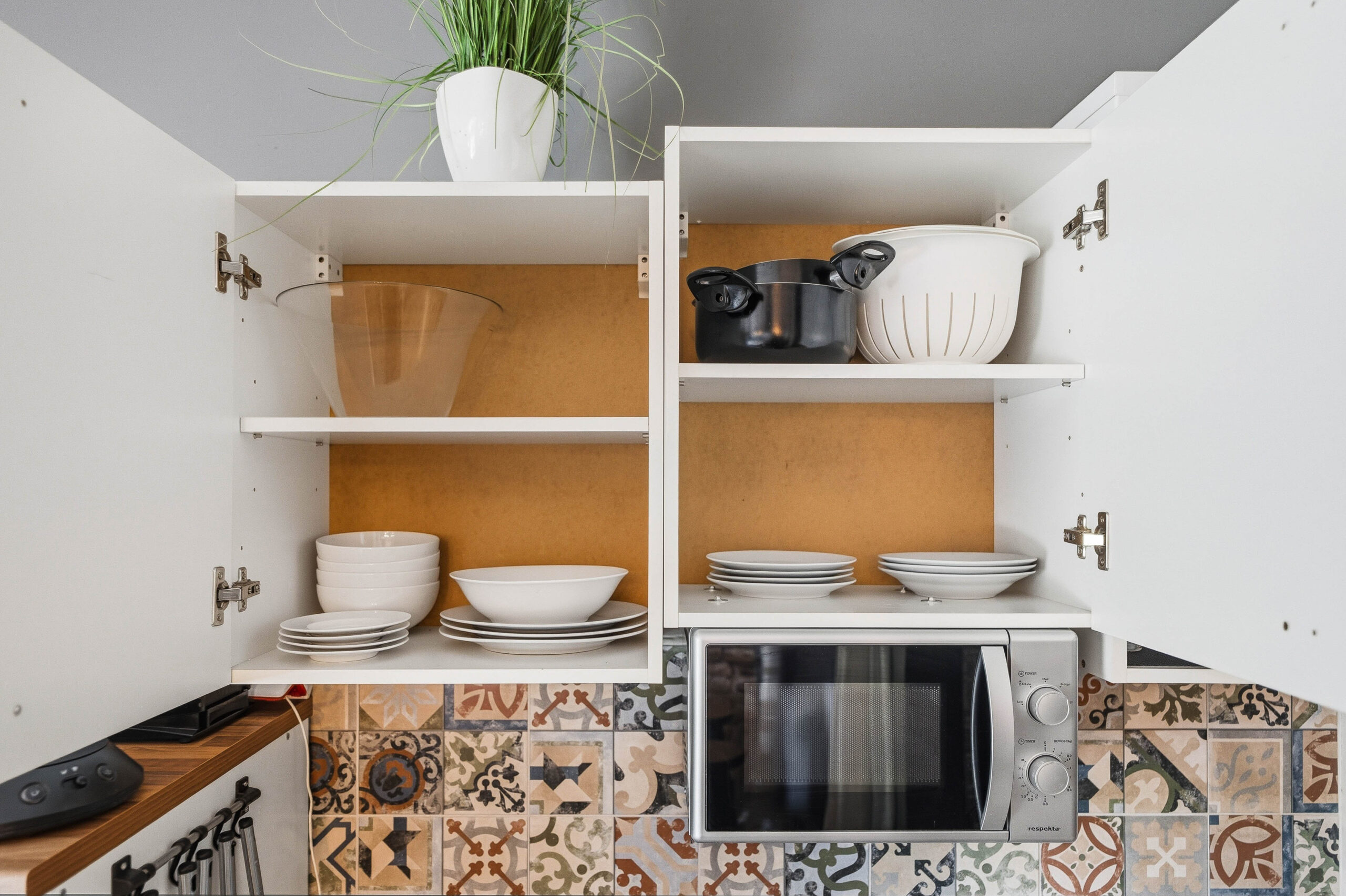Close-up of open cabinet with plates and microwave