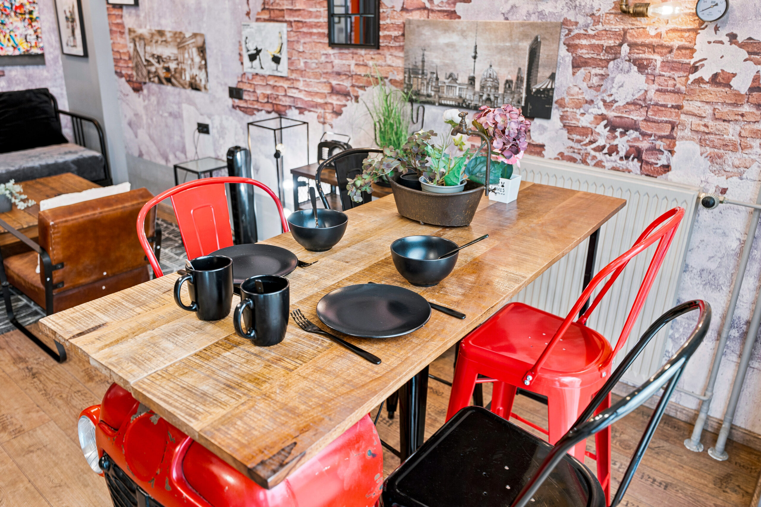 Wooden dining table with red chairs and kitchen area
