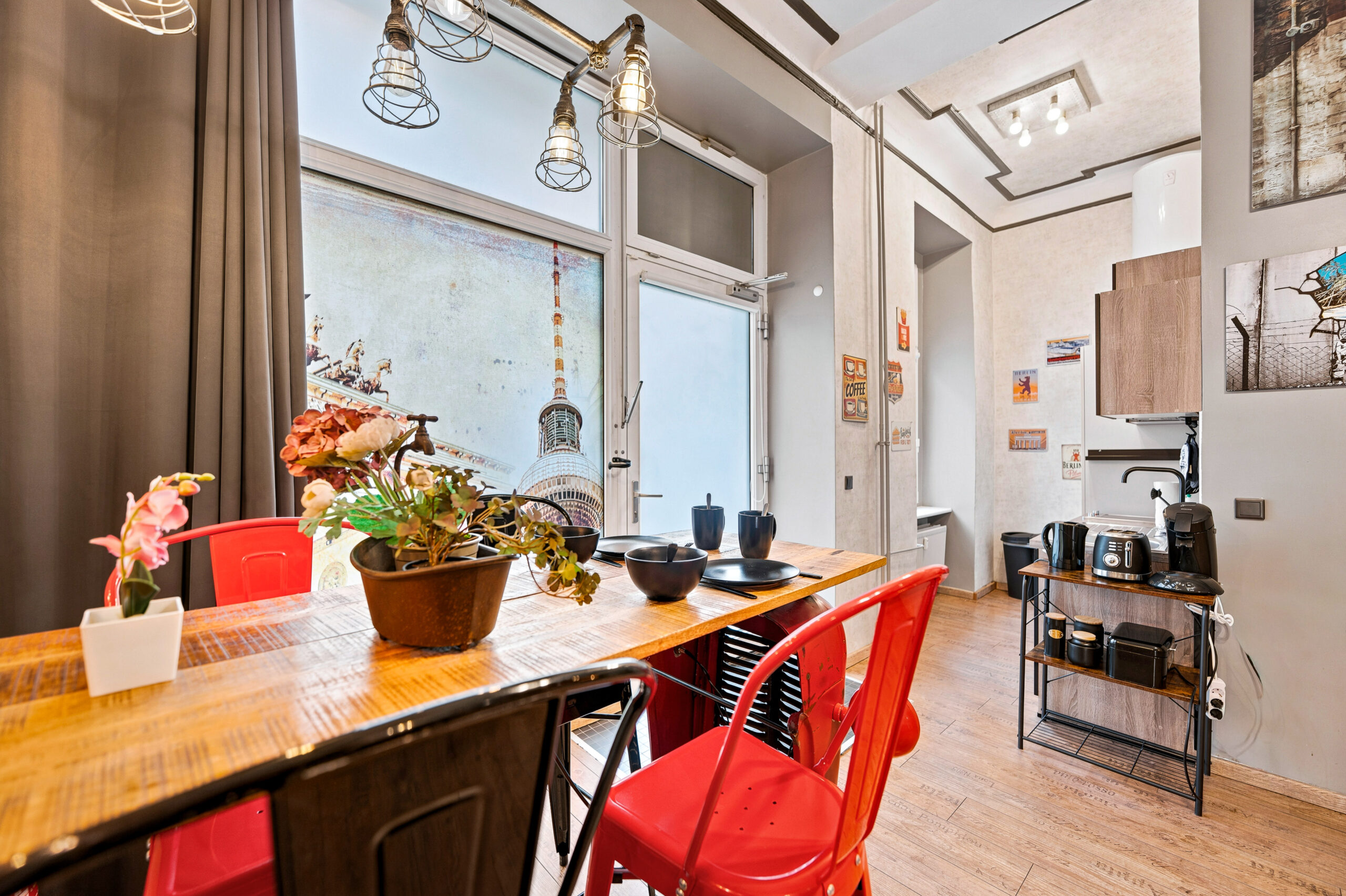 Wooden table with red chairs and large window cityscape
