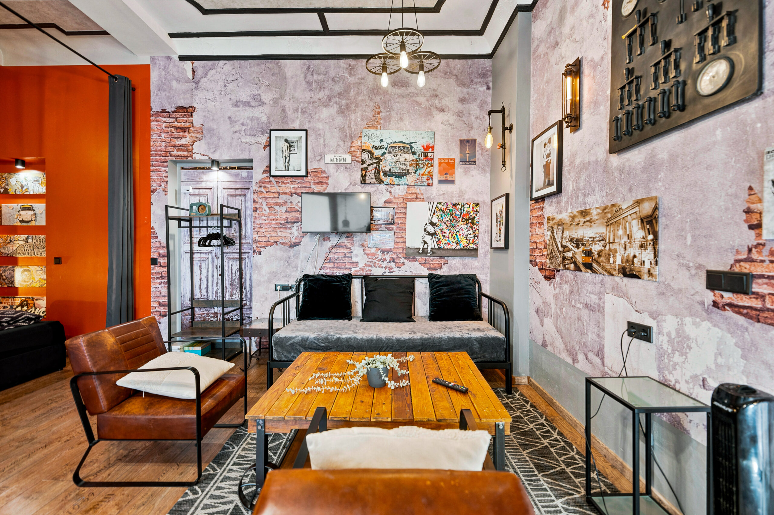 Multi-room open space with sofa, orange accent wall, kitchen
