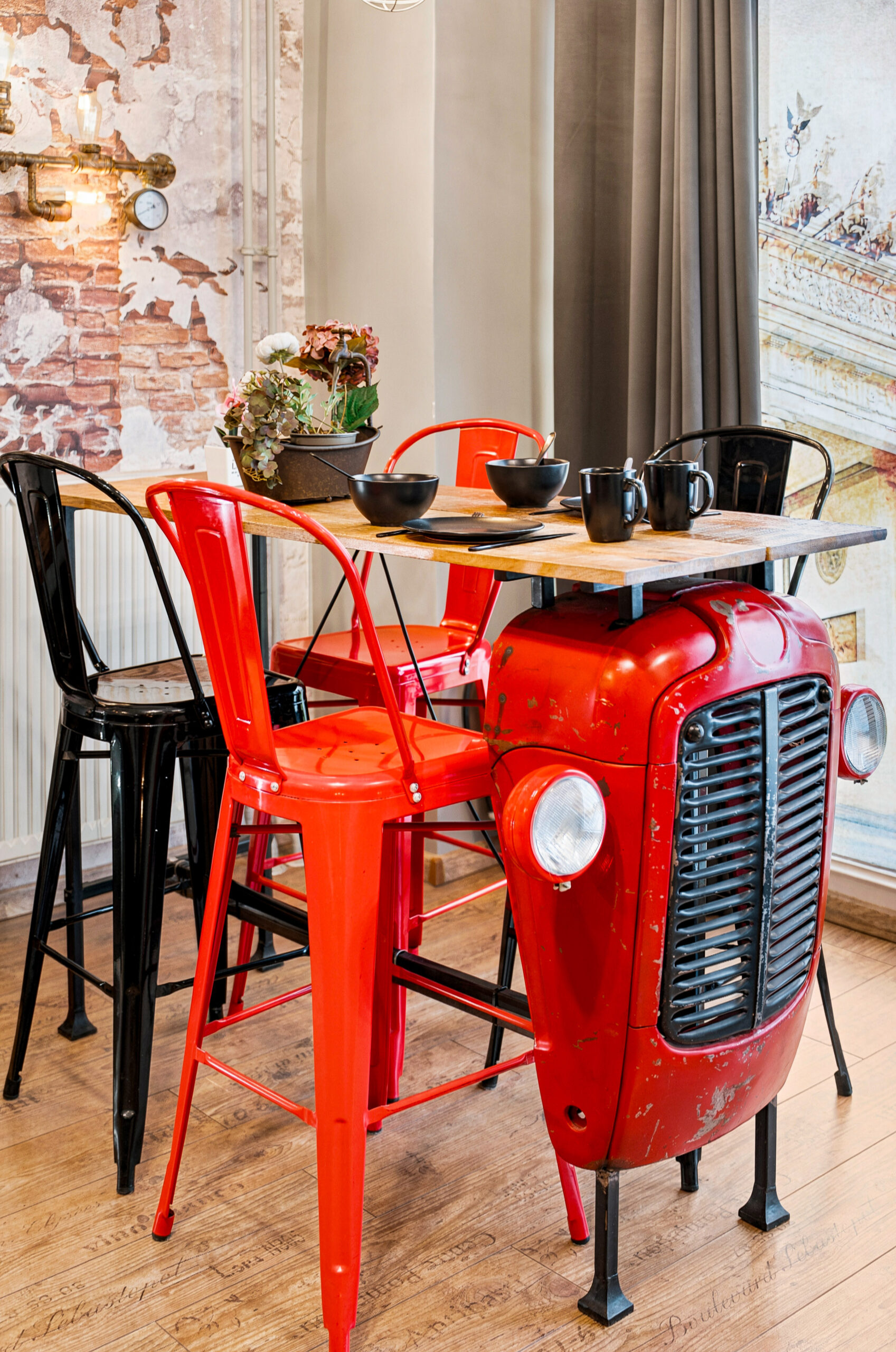 Red industrial table with black chairs and gray curtain