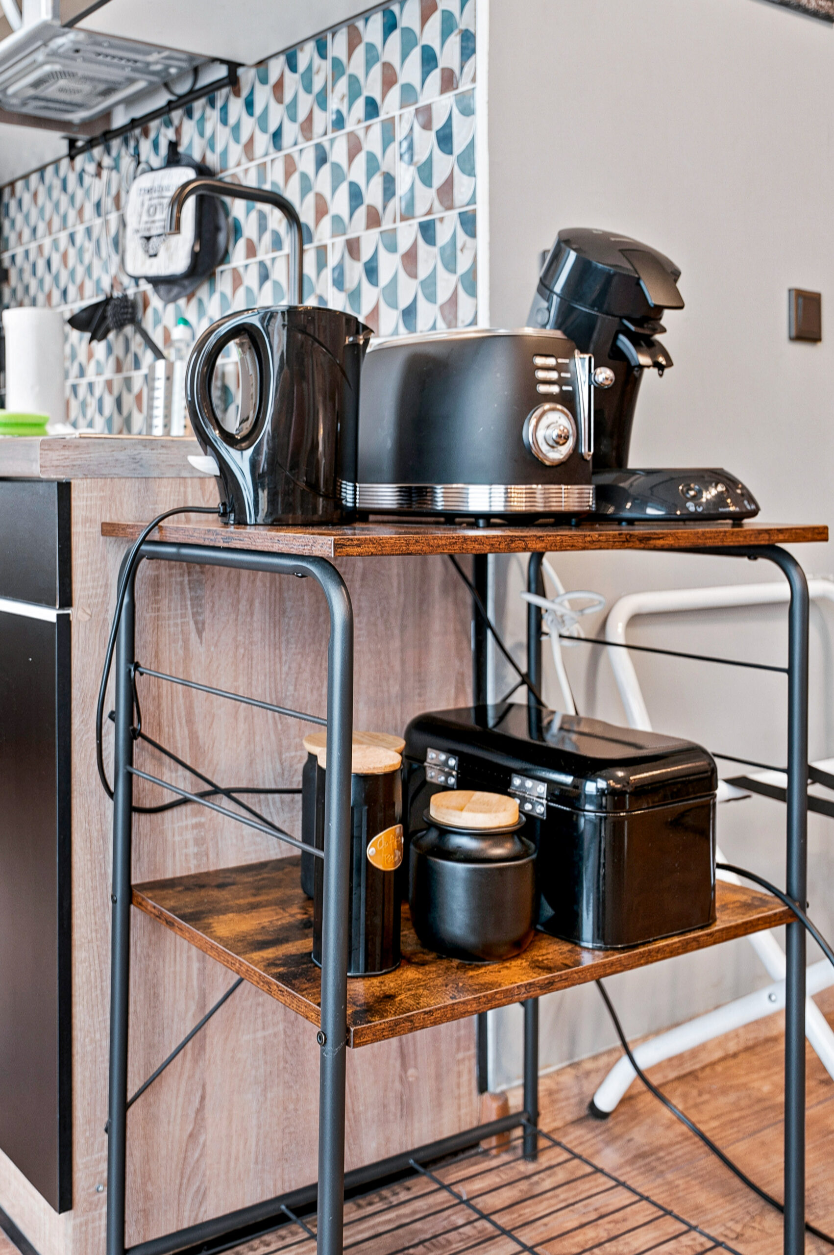 Compact kitchen with blue tiles and black appliances