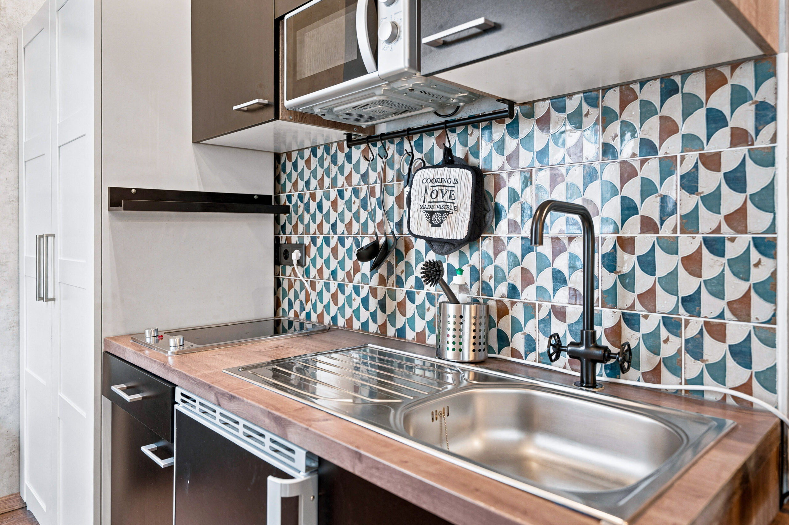 Small kitchenette with blue patterned backsplash and stainless sink