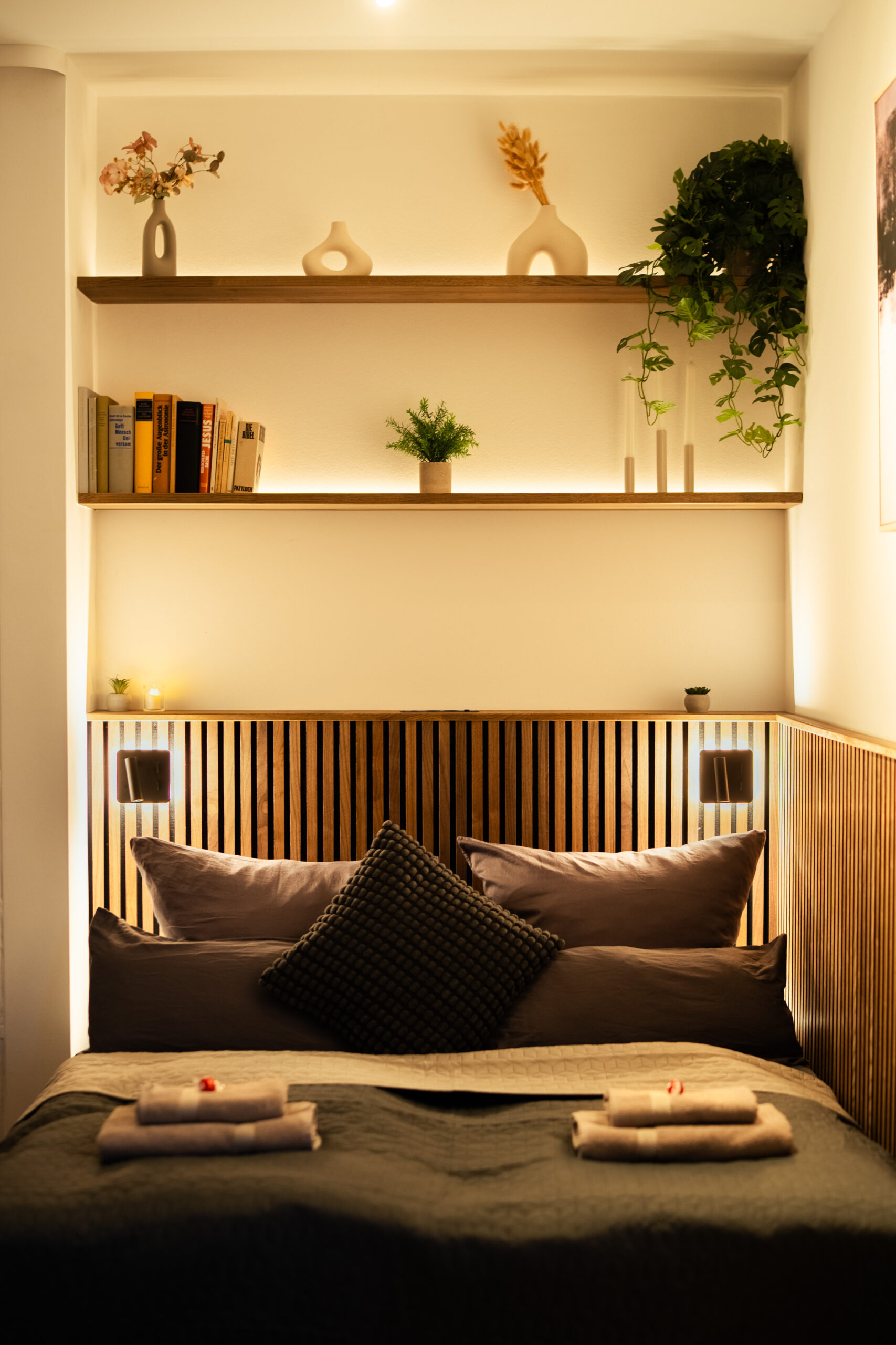 Compact bedroom nook with shelving and warm ambient lighting