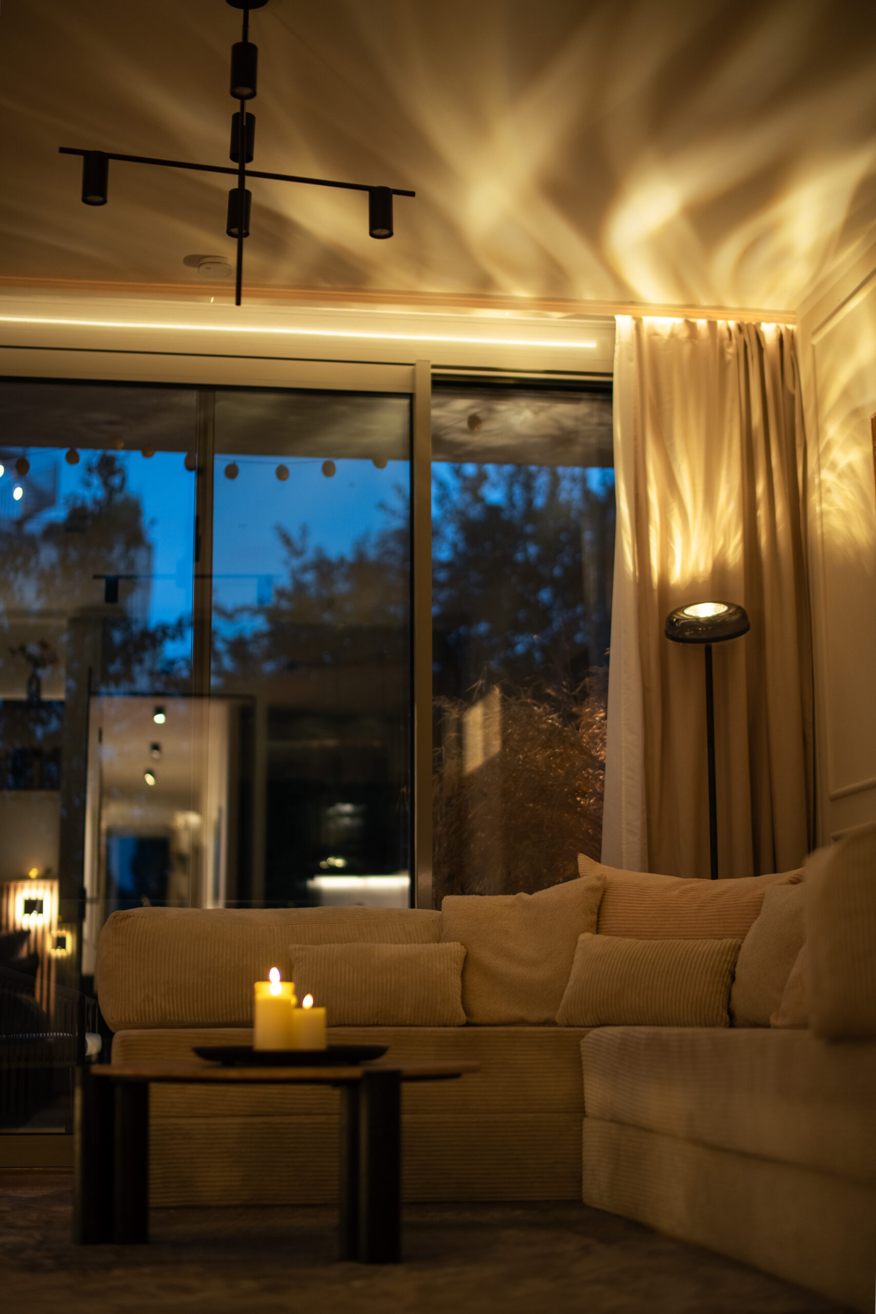 Evening living room with window view, sofa, and warm lighting