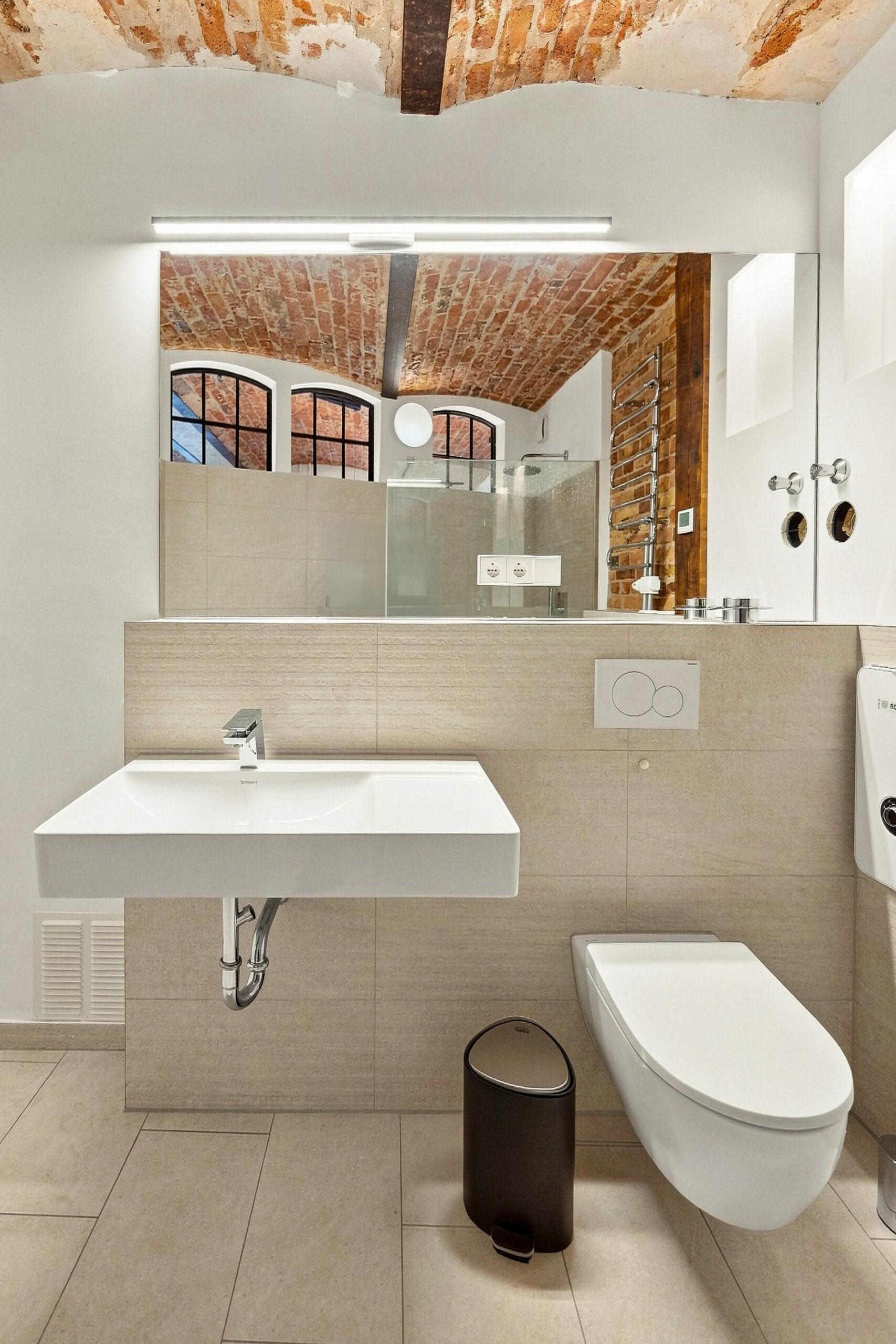 Contemporary bathroom with exposed brick, floating sink, and large mirror