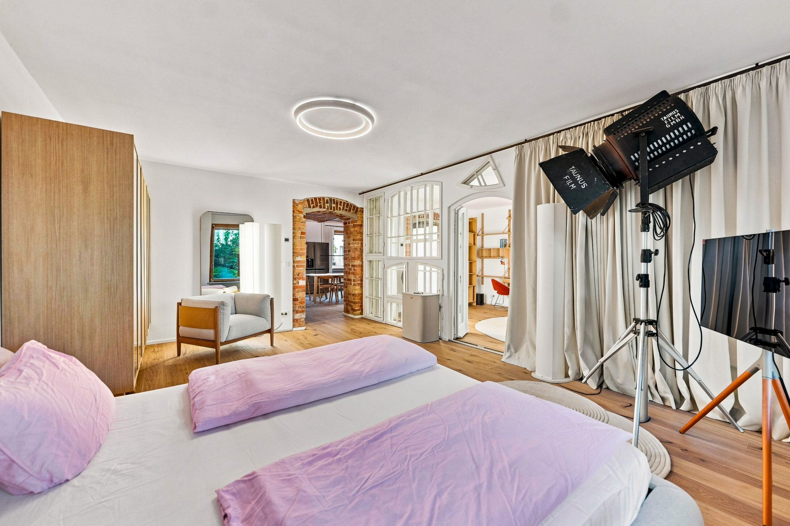 Spacious dual-bed bedroom with studio setup, wardrobe doors, ceiling light