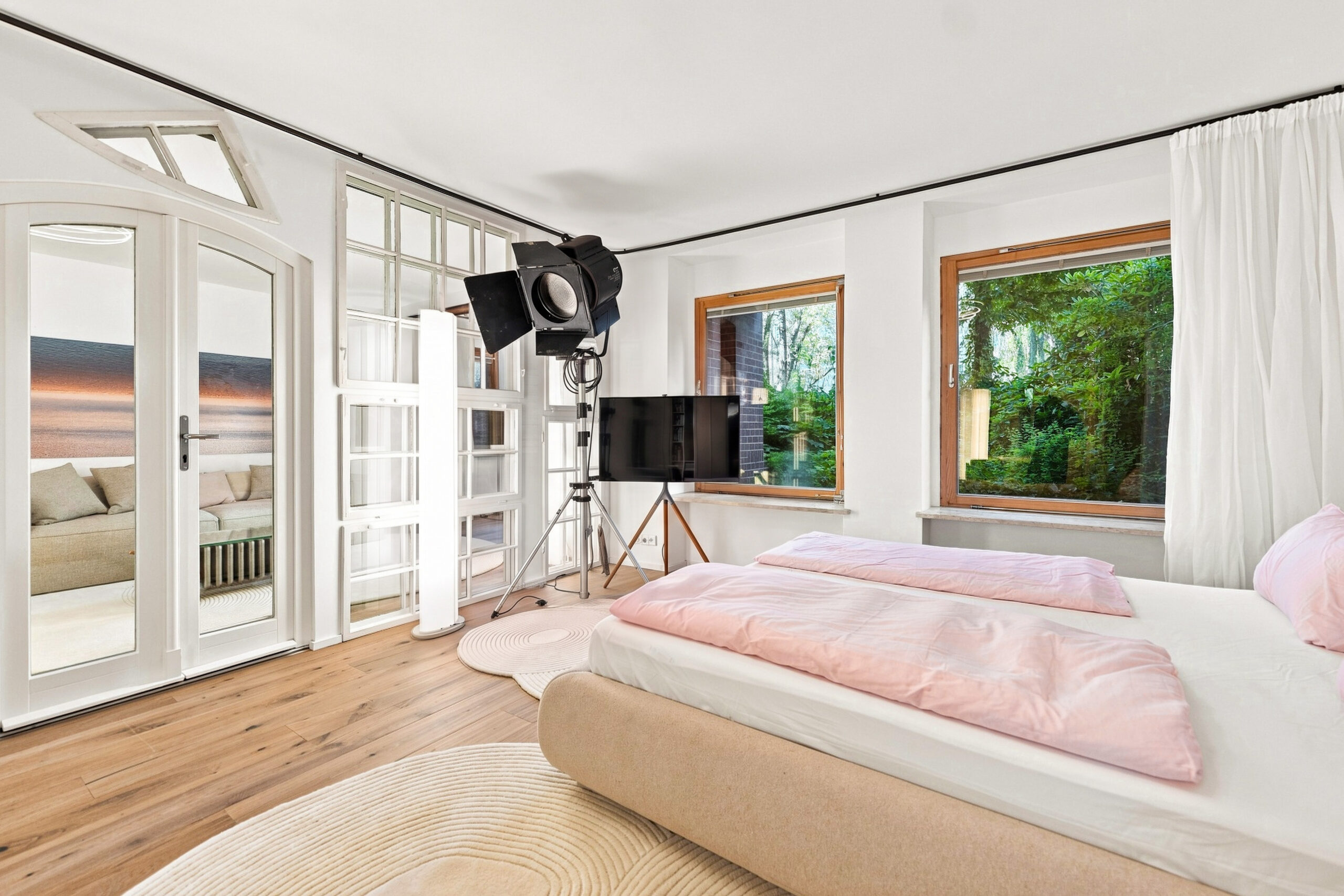 Bright bedroom with pink bedding, large windows, and contemporary furnishings