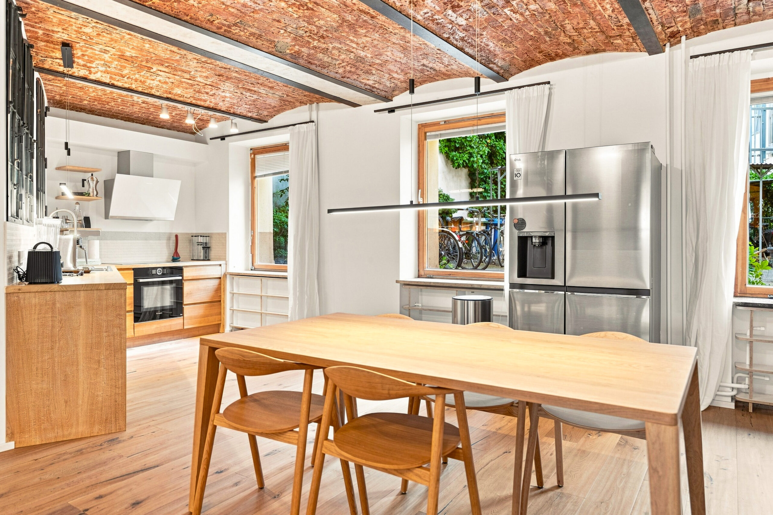 Industrial kitchen with brick ceiling, built-in shelving and dining area
