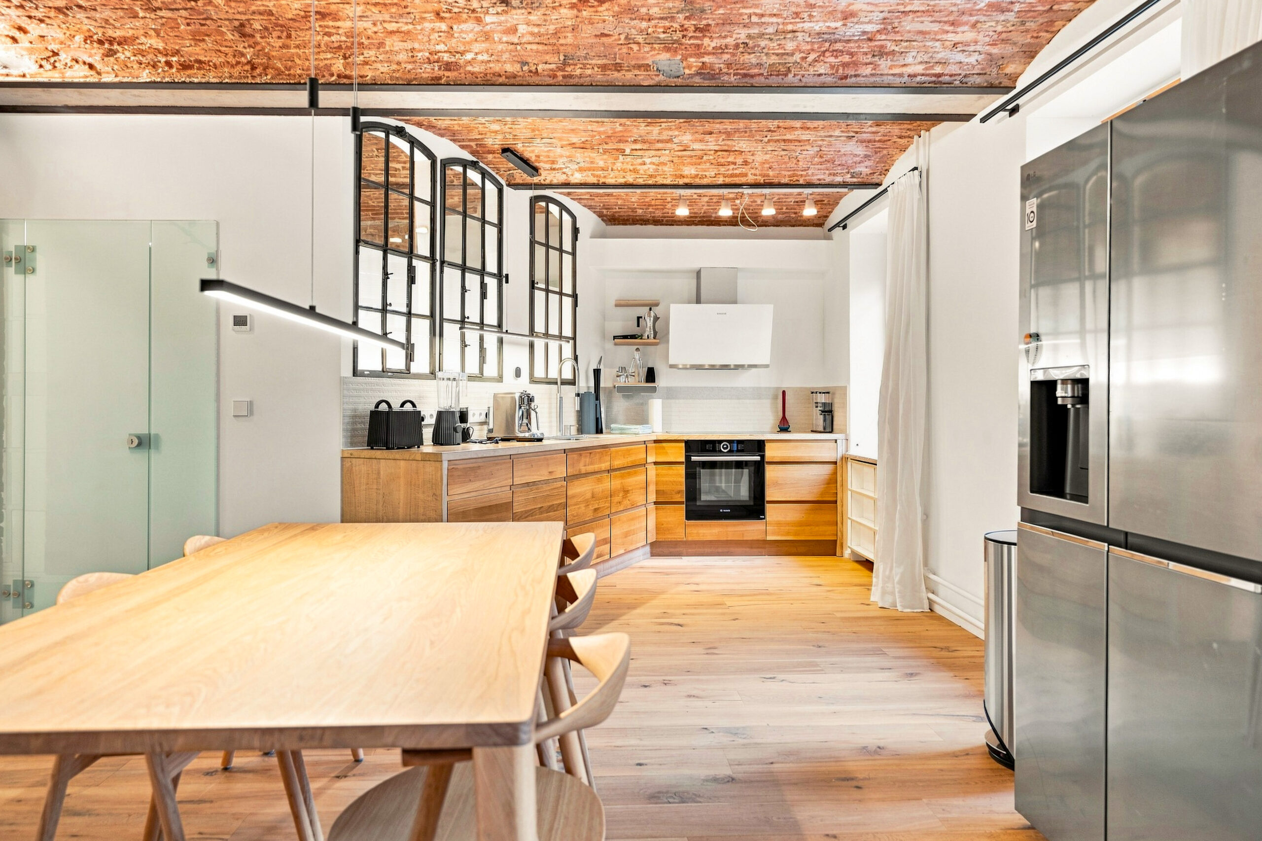 Modern kitchen with wooden table, stainless appliances and brick walls