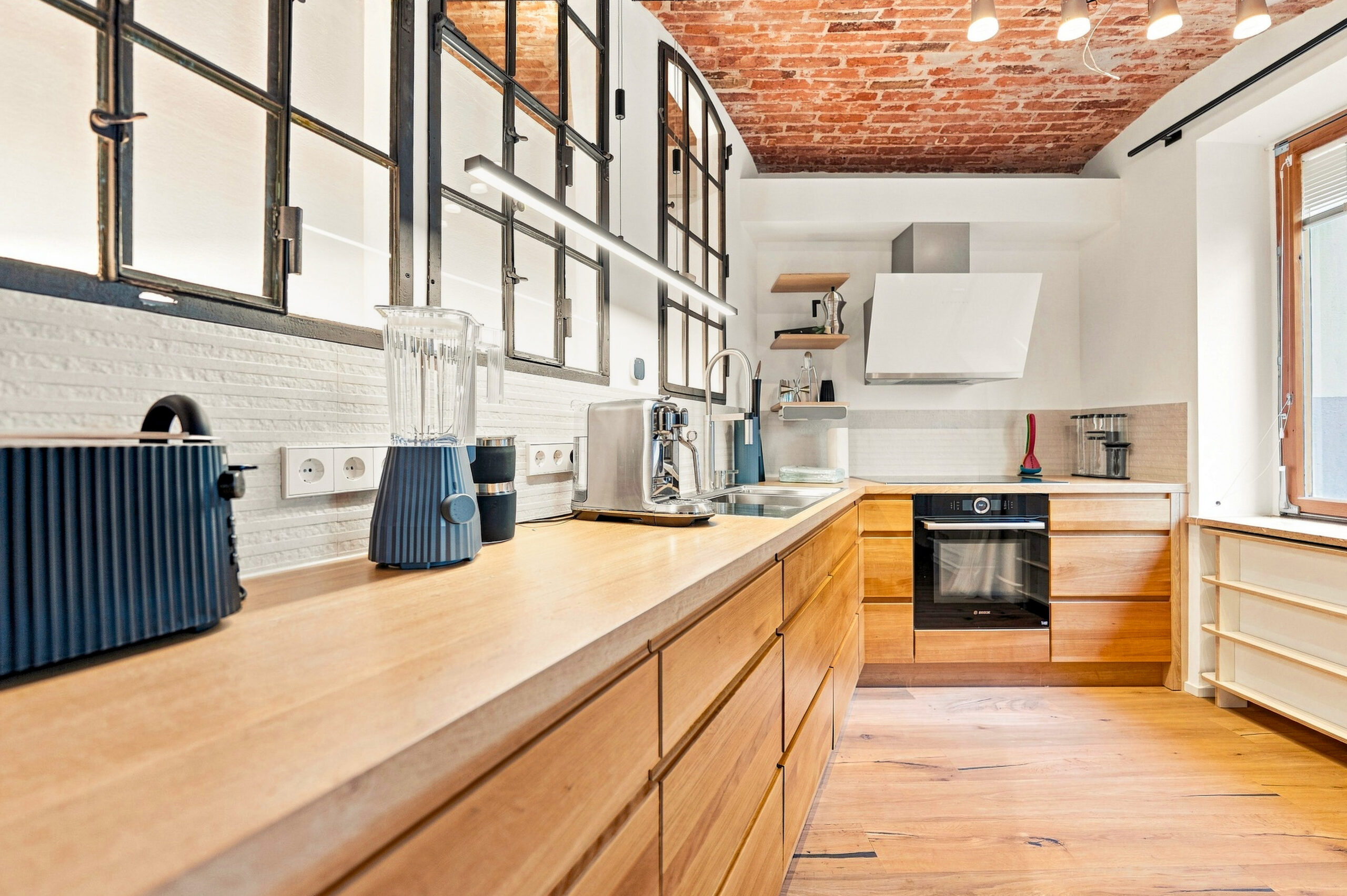 Spacious kitchen with wooden counters, brick ceiling, and white cabinetry