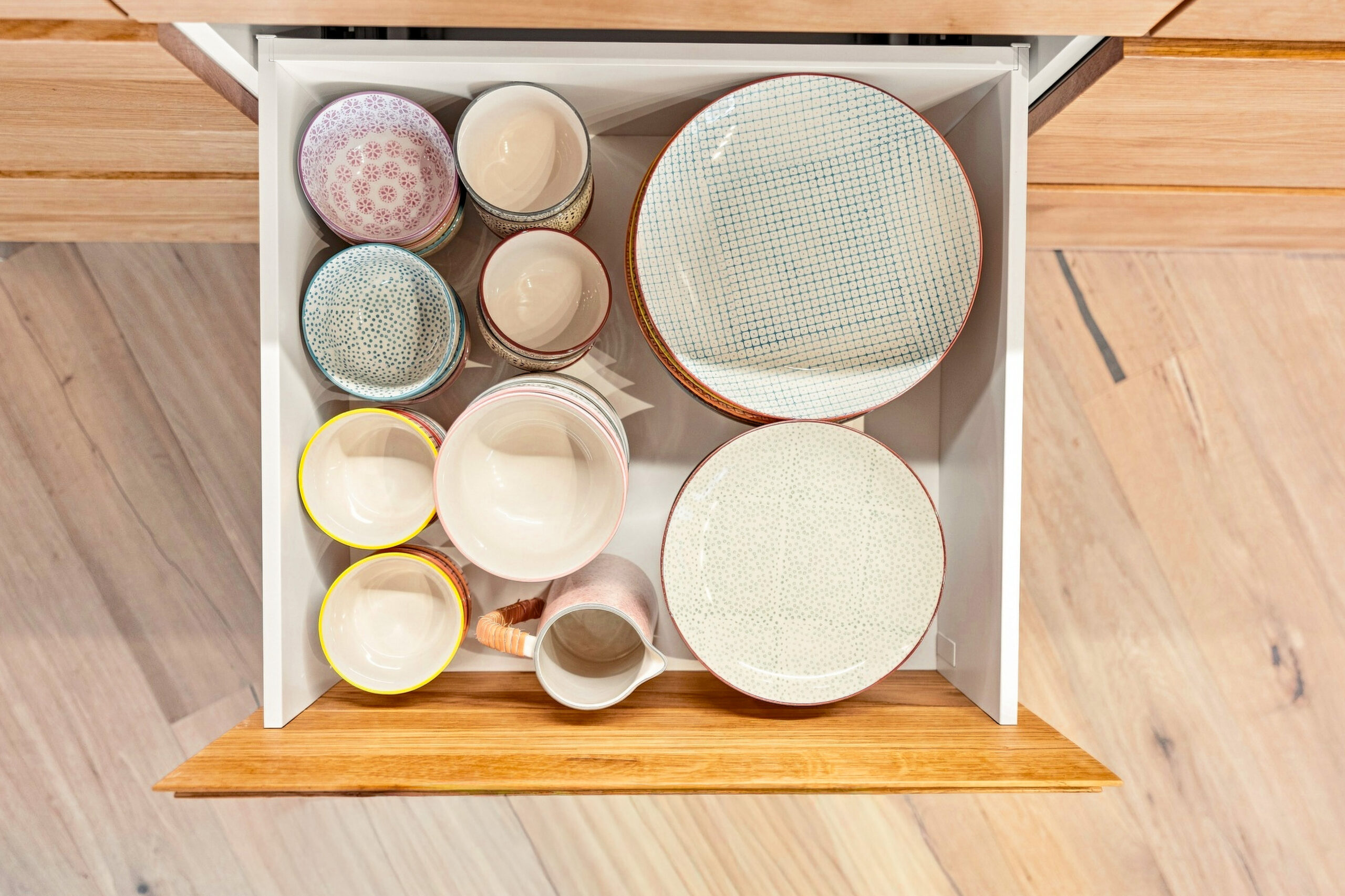Overhead view of kitchen drawer with neatly arranged bowls and strainers