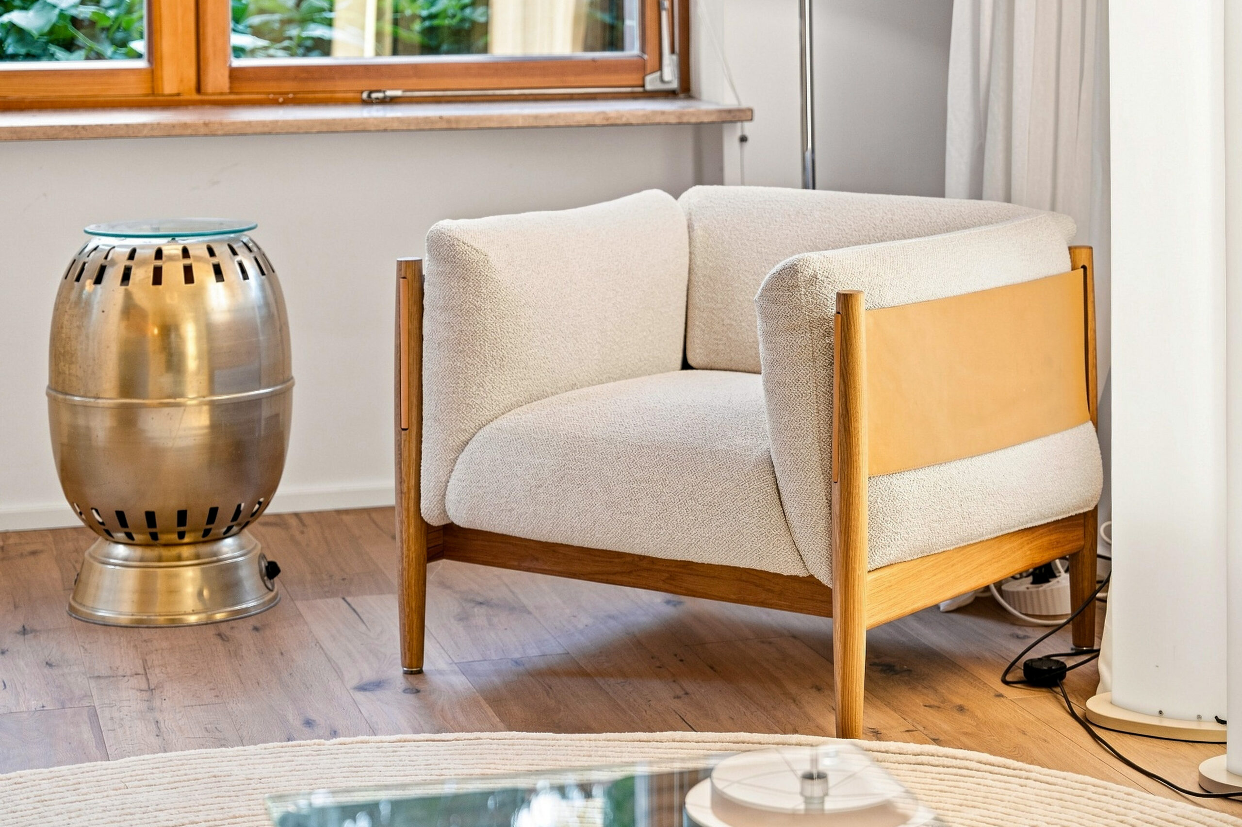 Cream upholstered chair detail with wooden frame and metallic accents