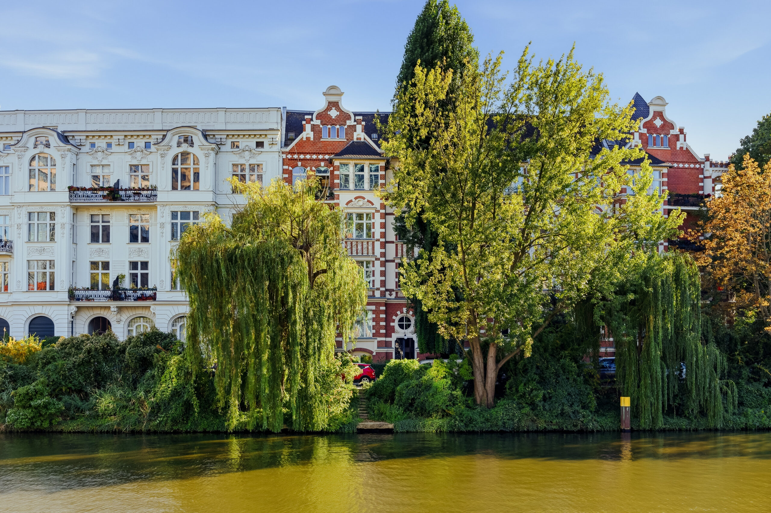 Period buildings reflected in river with mature poplar trees