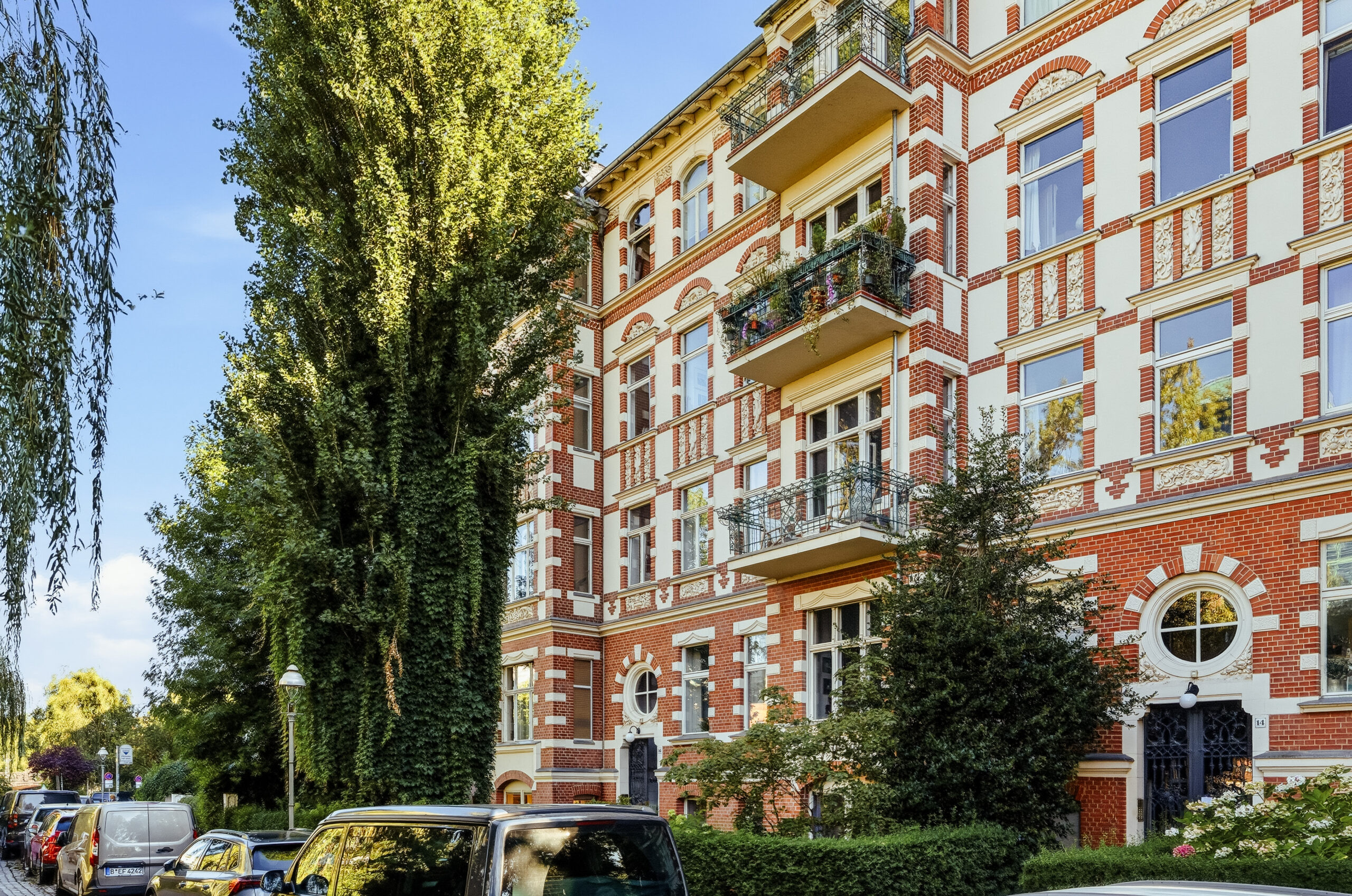 Ornate terracotta brick apartment building with ivy and trees