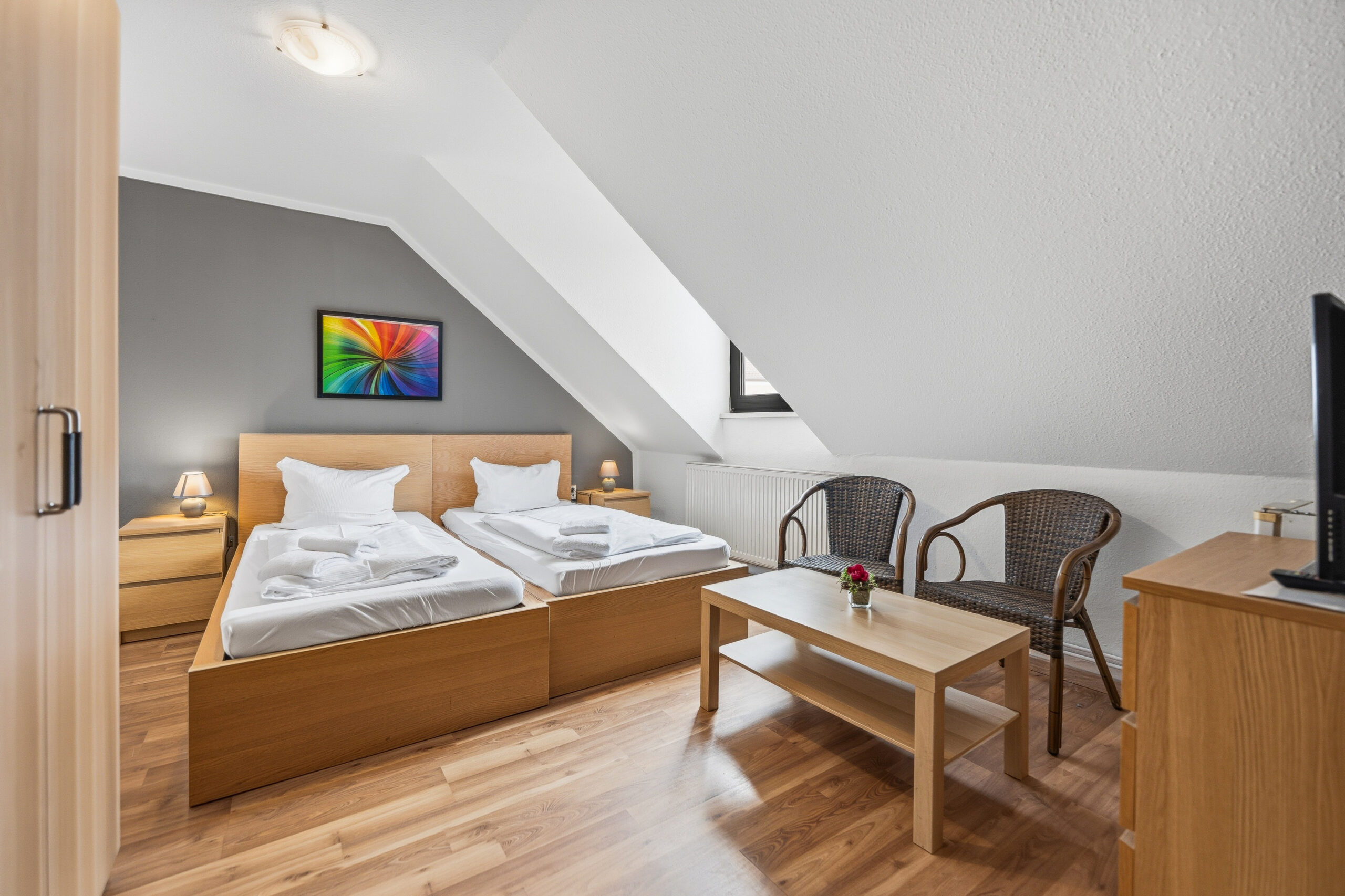 Attic twin room with seating area and colorful art
