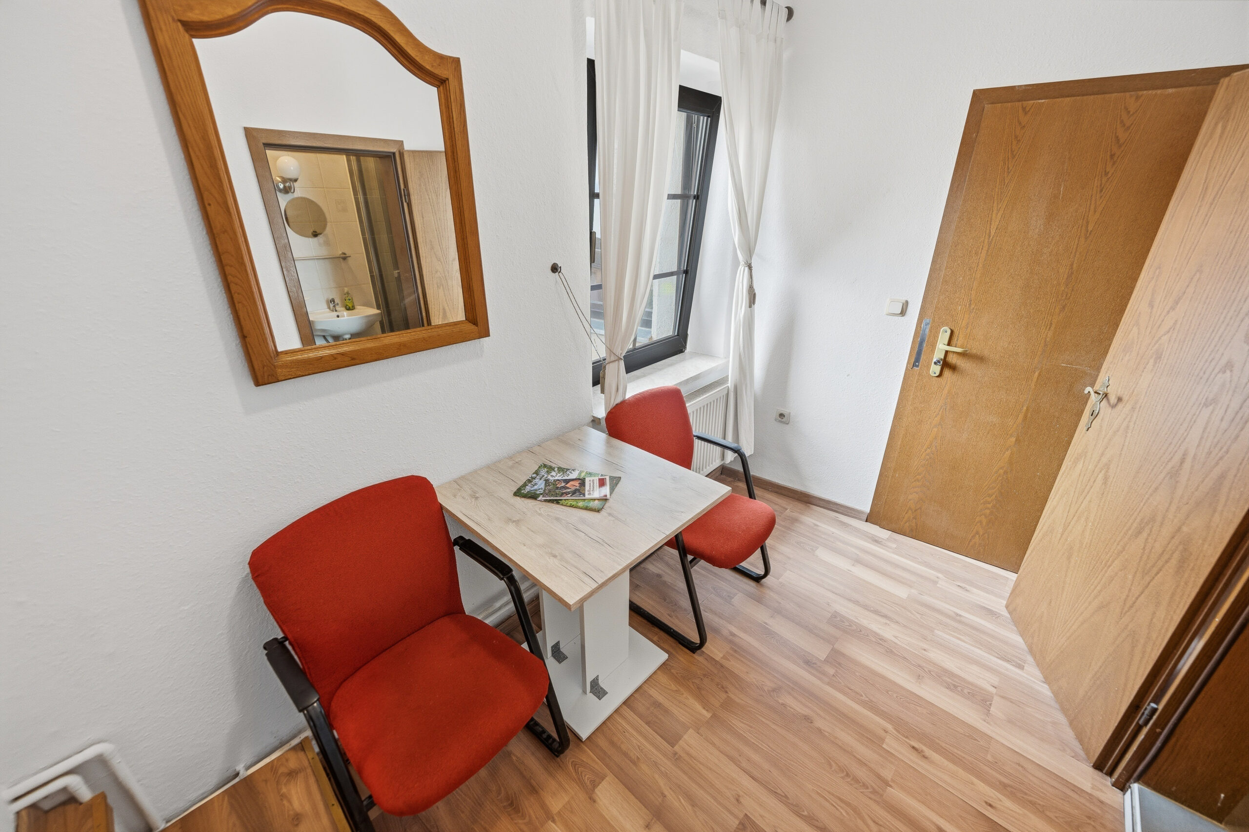 Small seating nook with red chairs and mirror