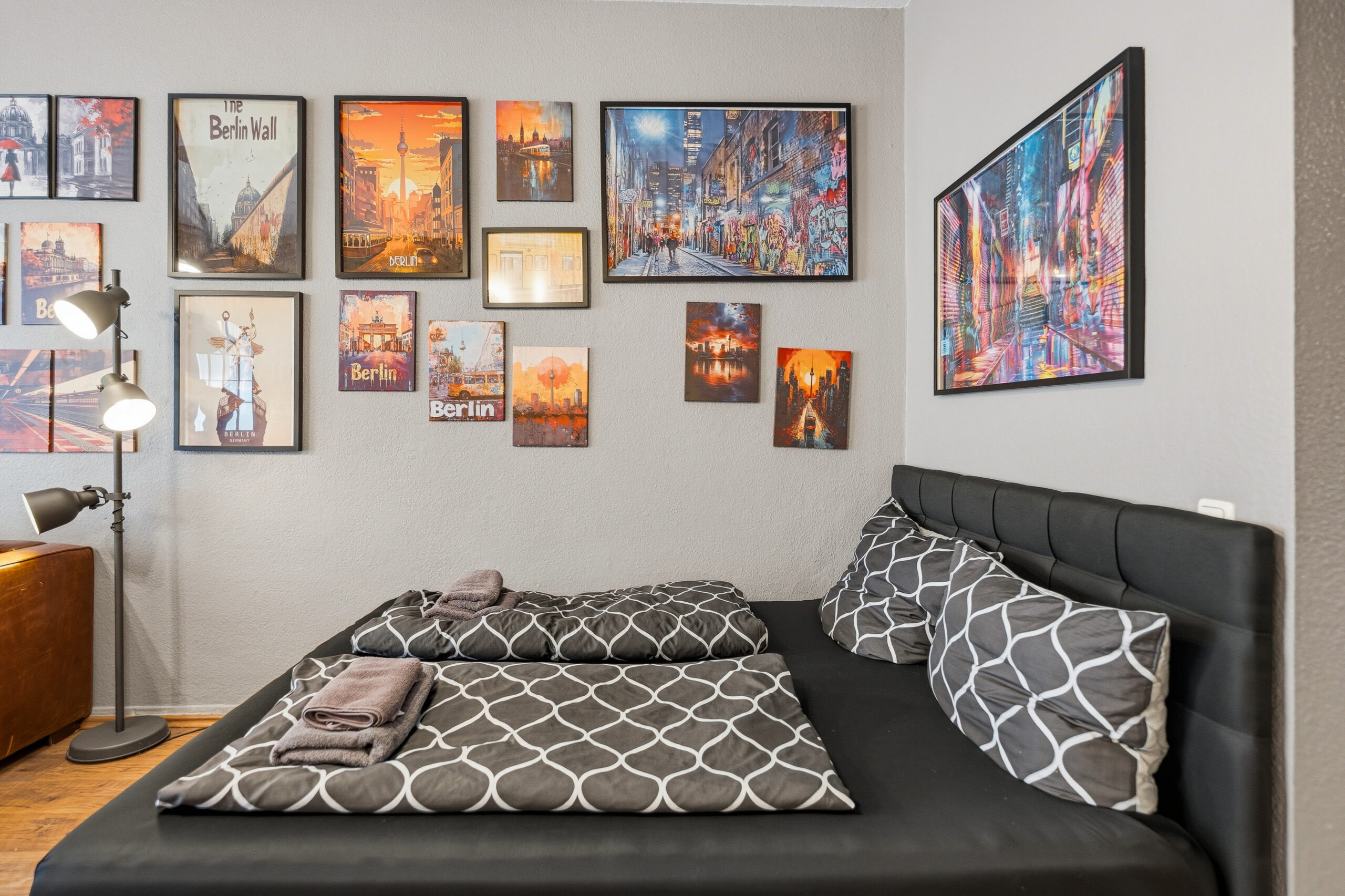 Bed with patterned bedding under framed city photos