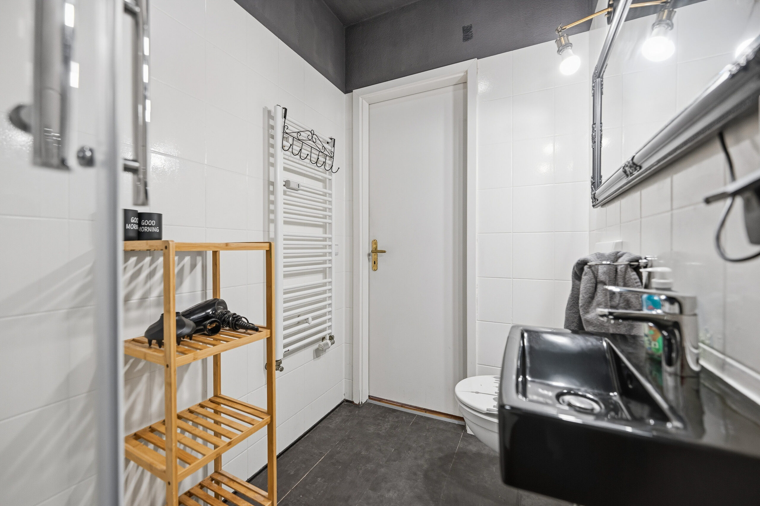 Bathroom with black sink, towel rack, and shelving