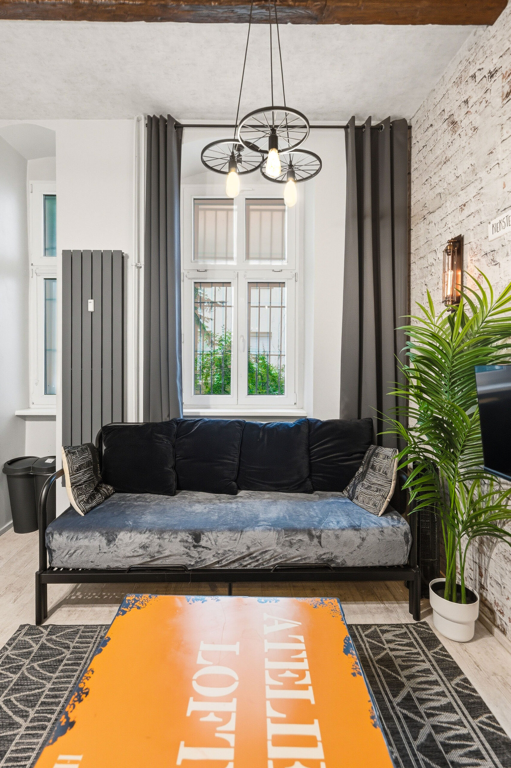 Living room with black sofa, tall windows, and orange rug