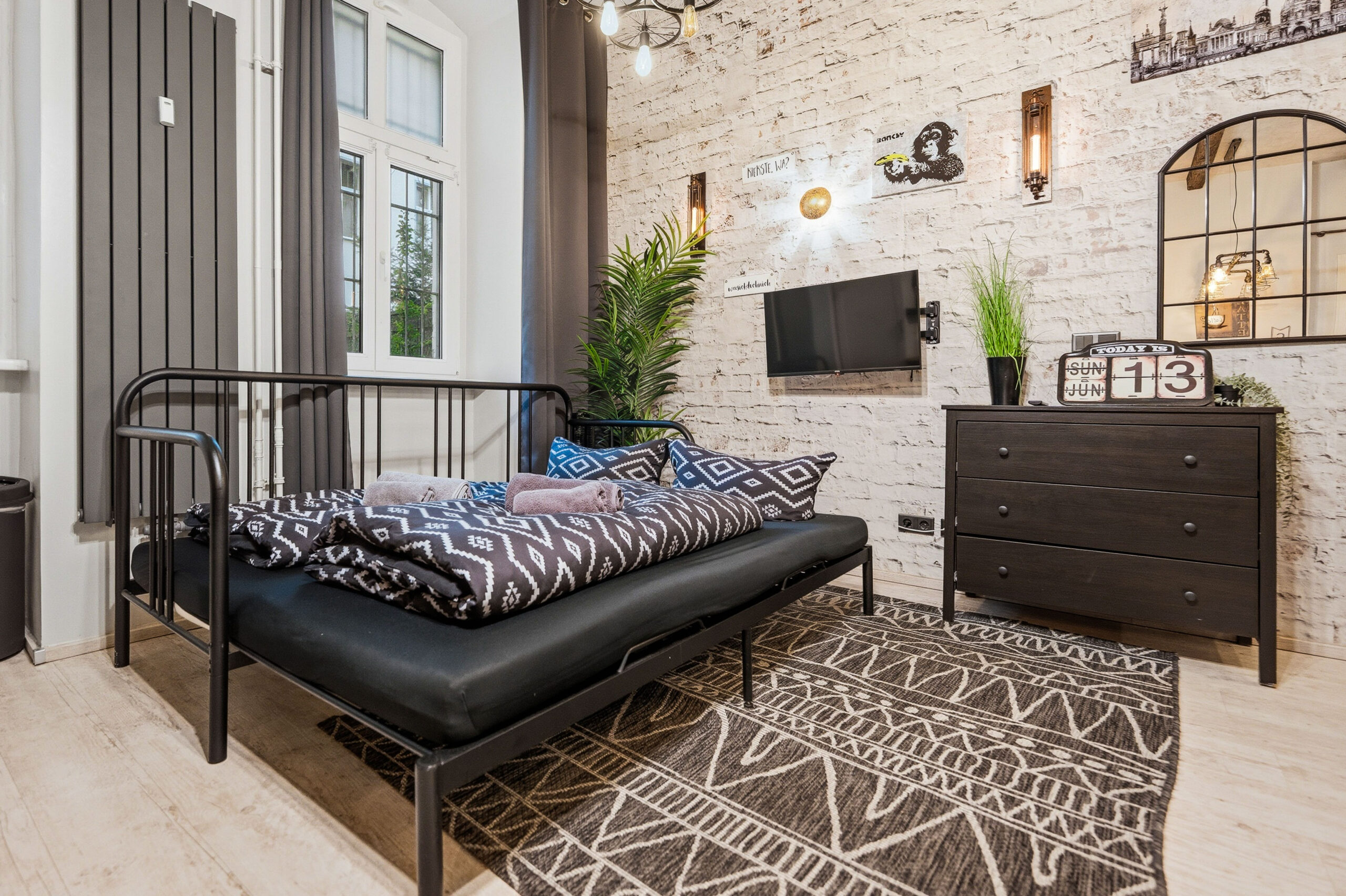 Industrial bedroom with black metal bed frame and dark furniture on geometric rug