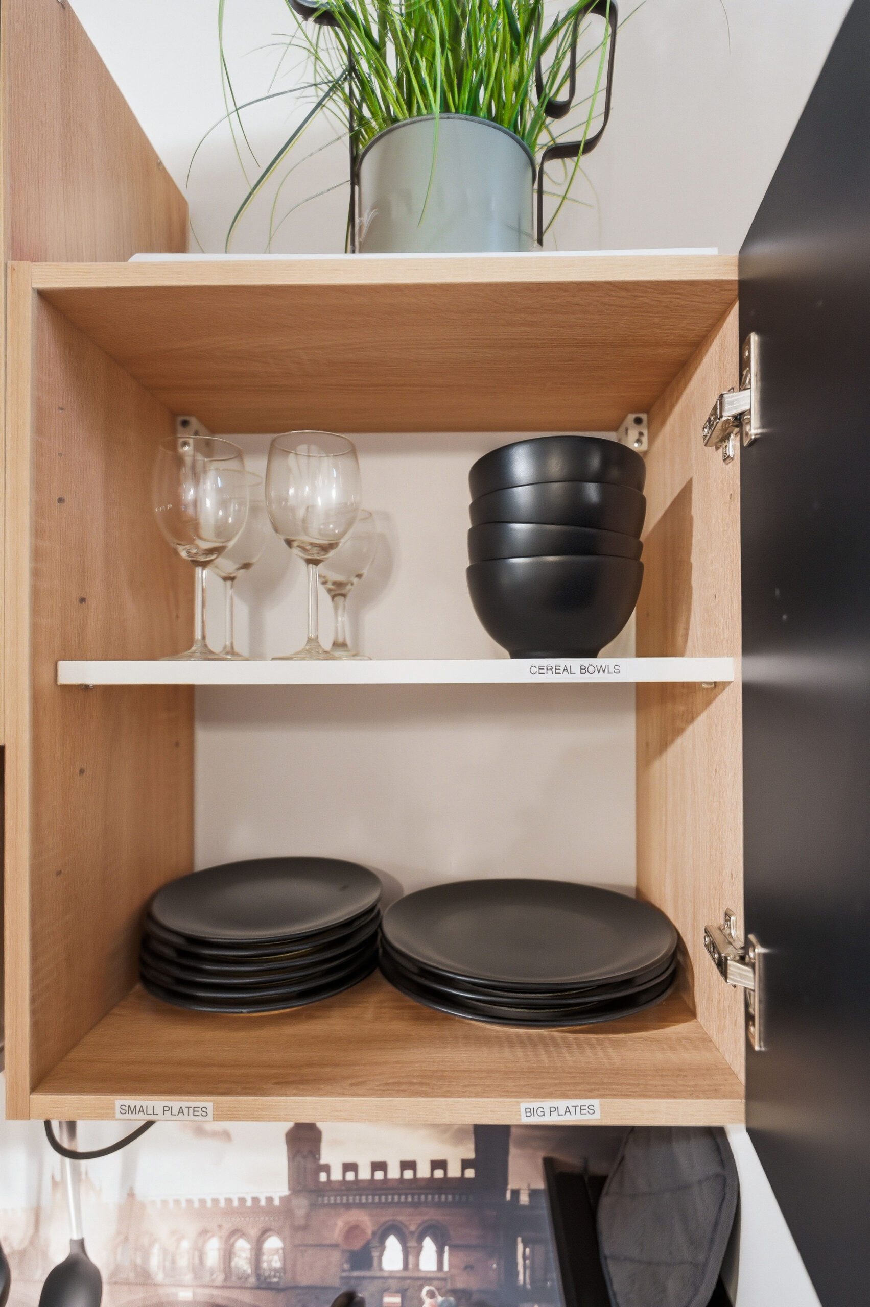 Wooden cabinet shelving with black plates and glassware storage