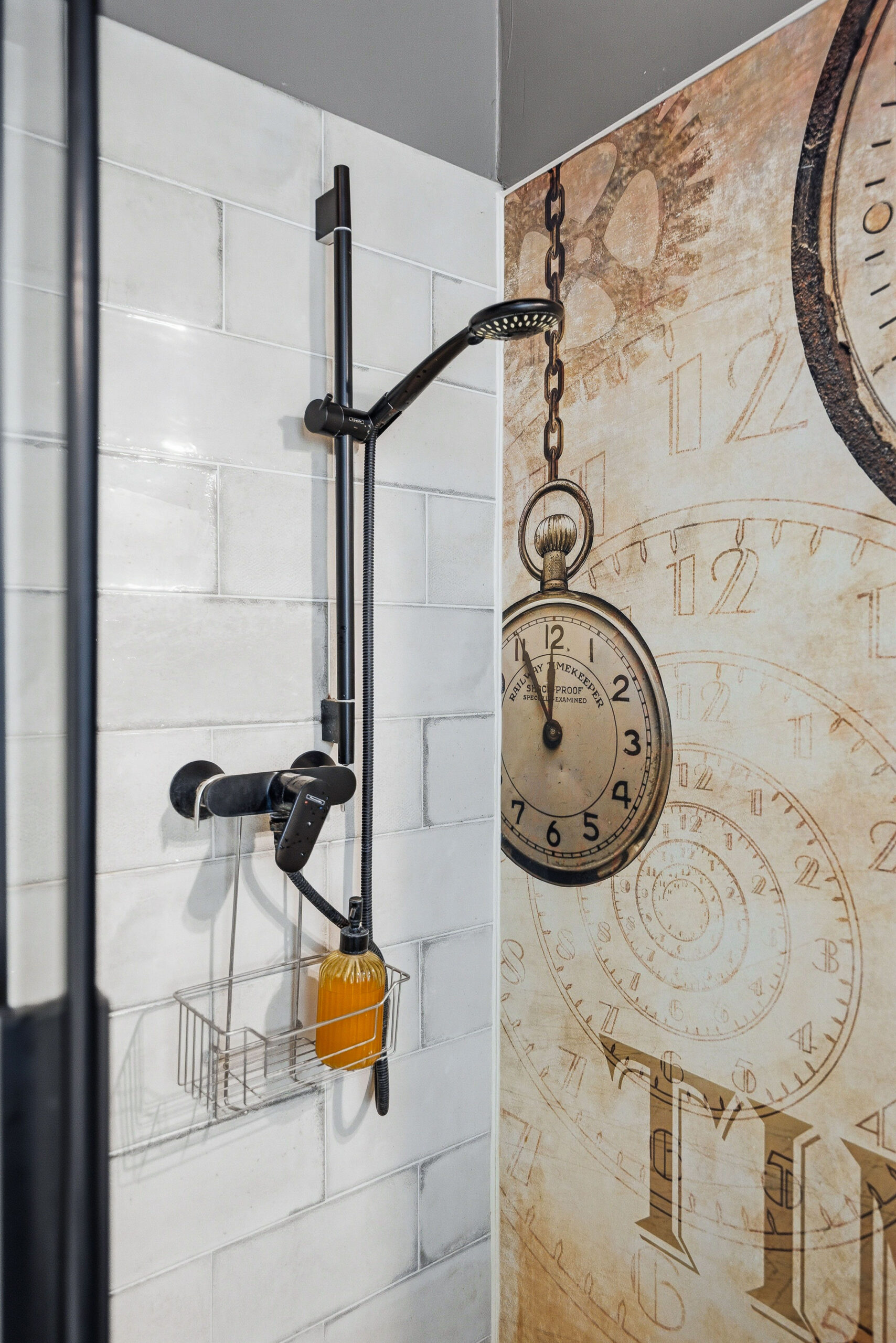 Shower area with black fixtures, white tiles and hanging decorative elements