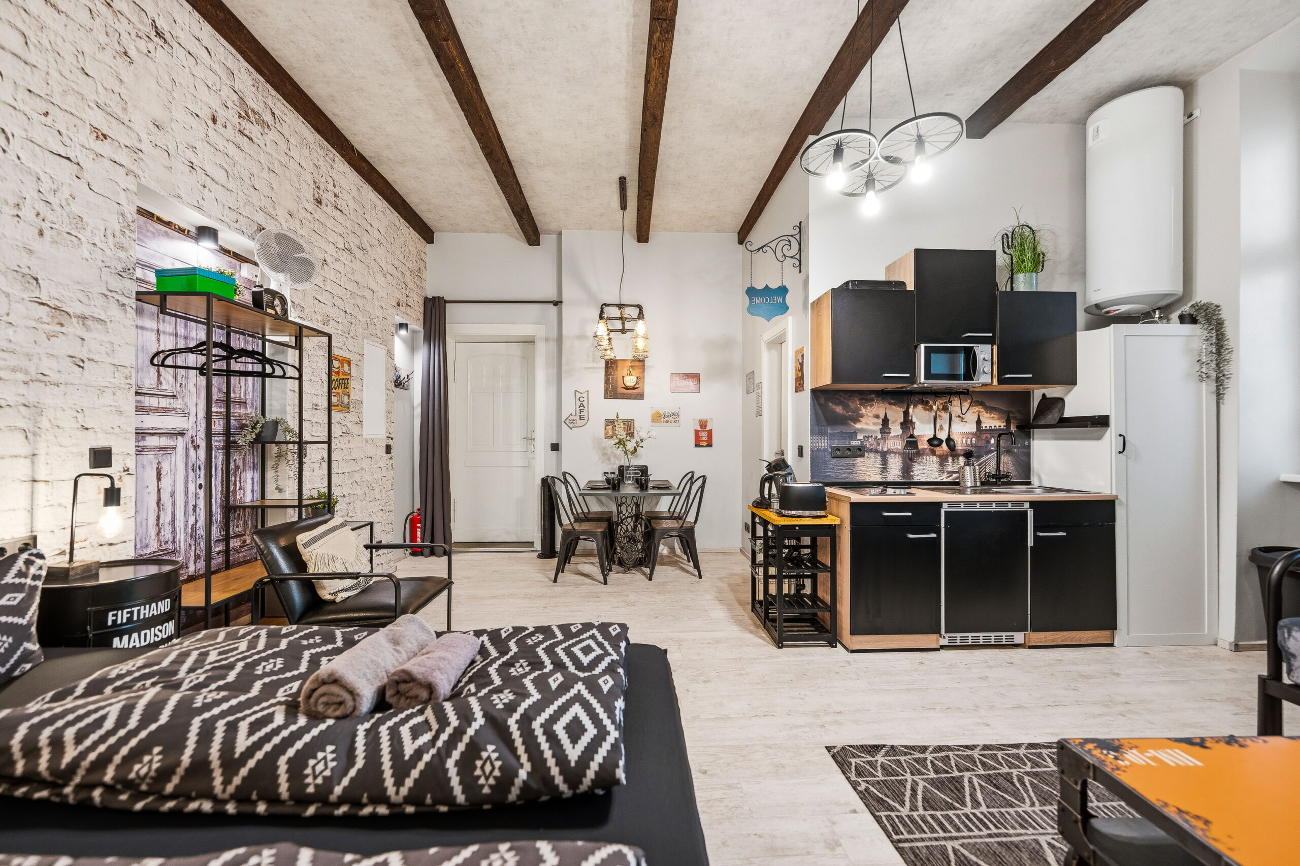 Full living area with bed, sofa, dining, and exposed brick
