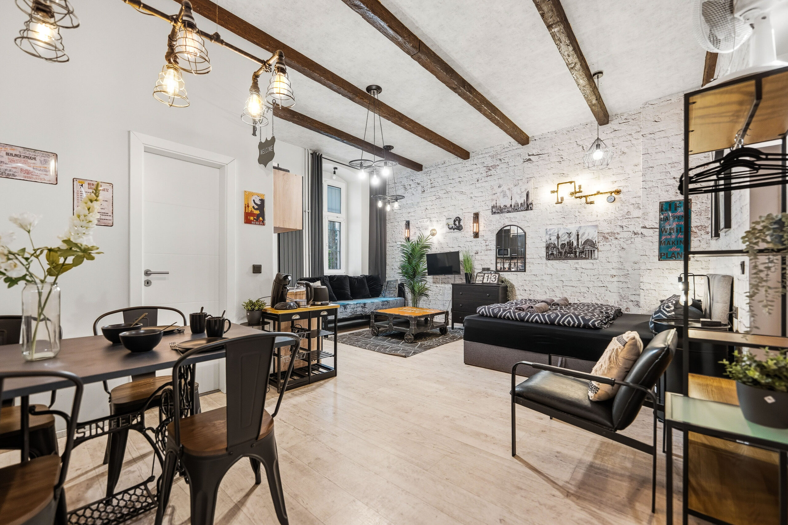 Wide living room with black sofa, timber beams, and plants