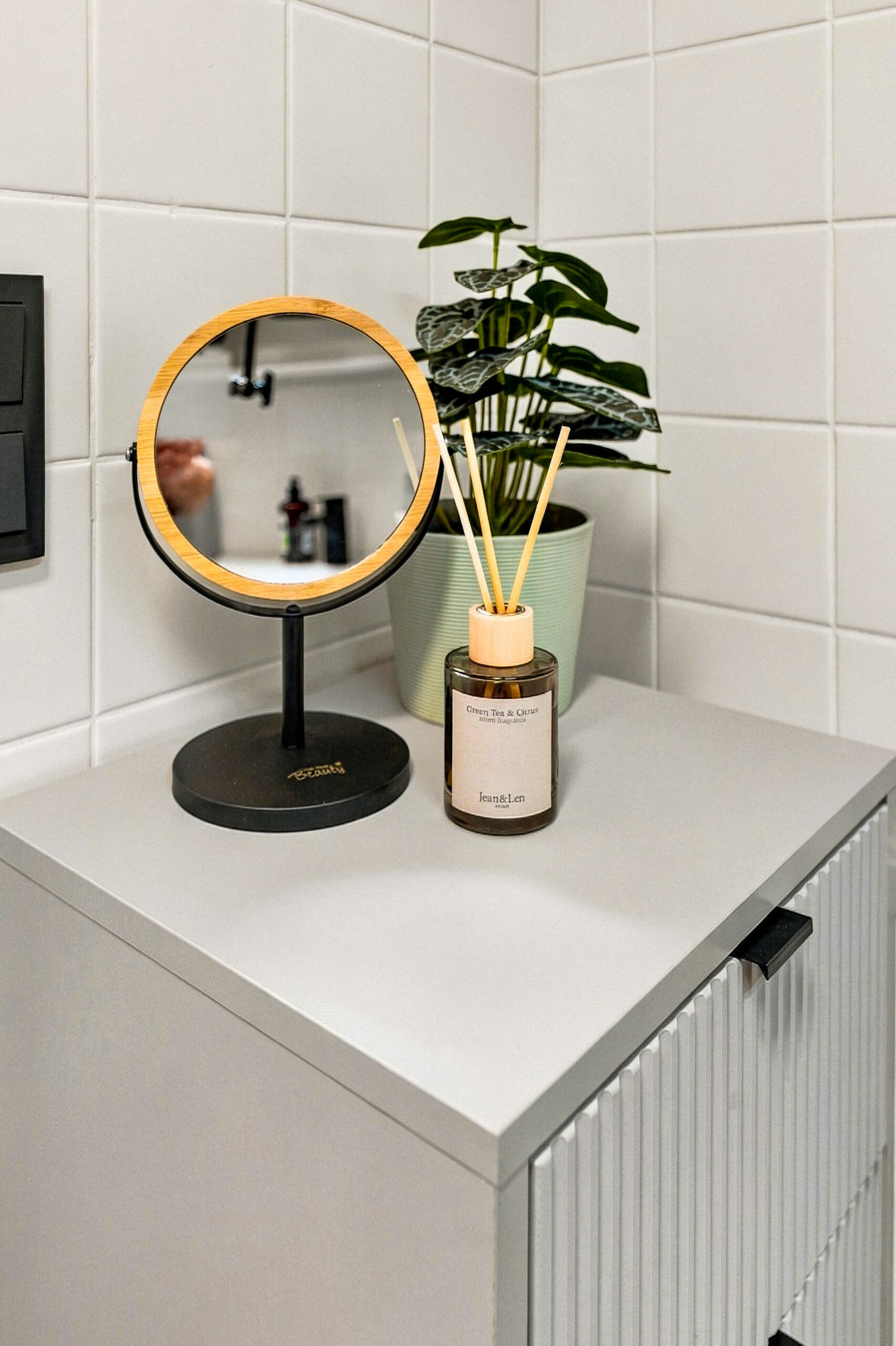 Round mirror and plant on bathroom cabinet corner
