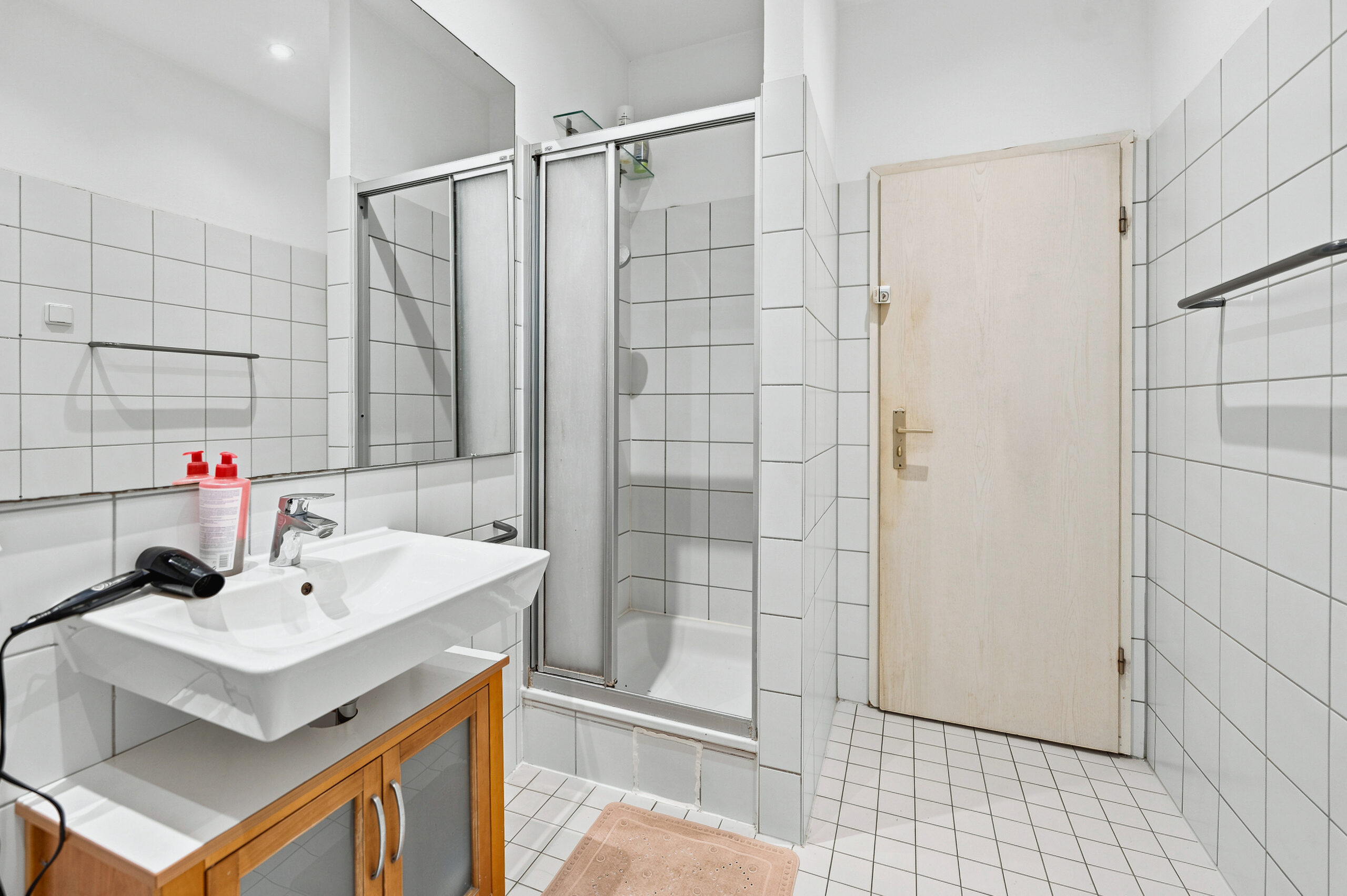 Bathroom with wooden vanity, shower enclosure and tiled walls