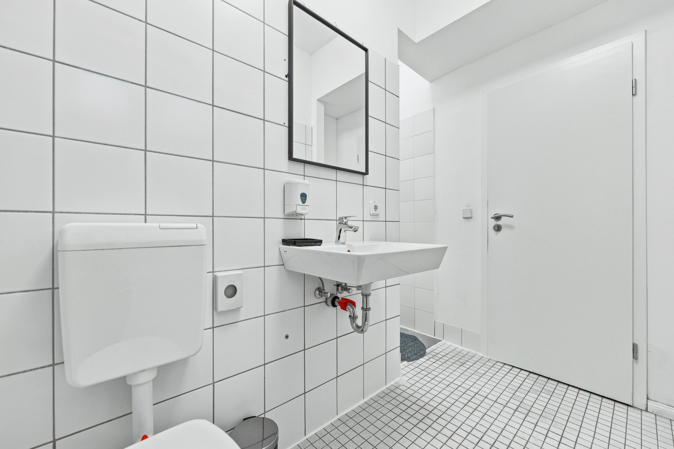 Small white tiled bathroom with toilet and pedestal sink
