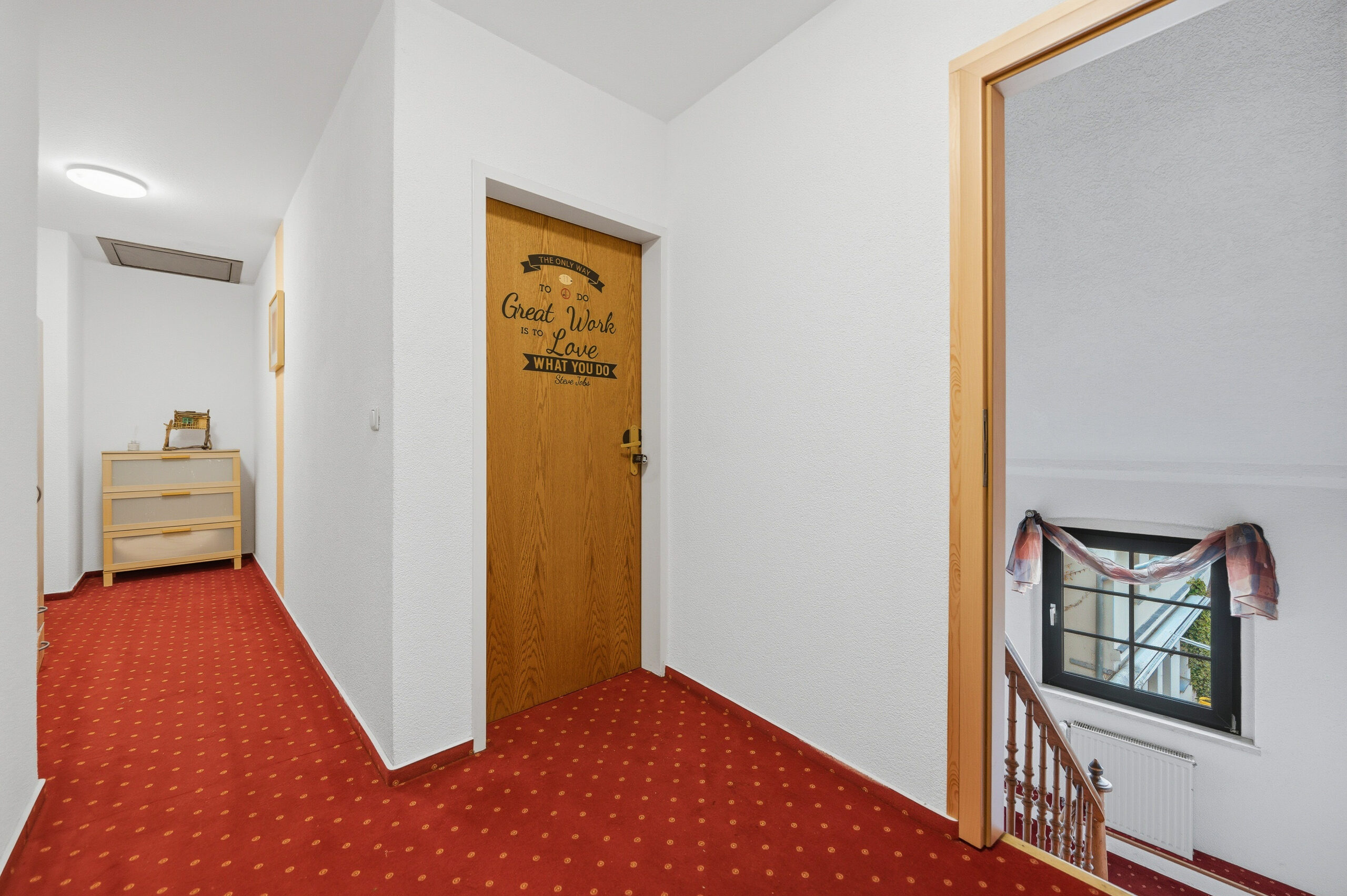 Hallway with red carpet and wooden door