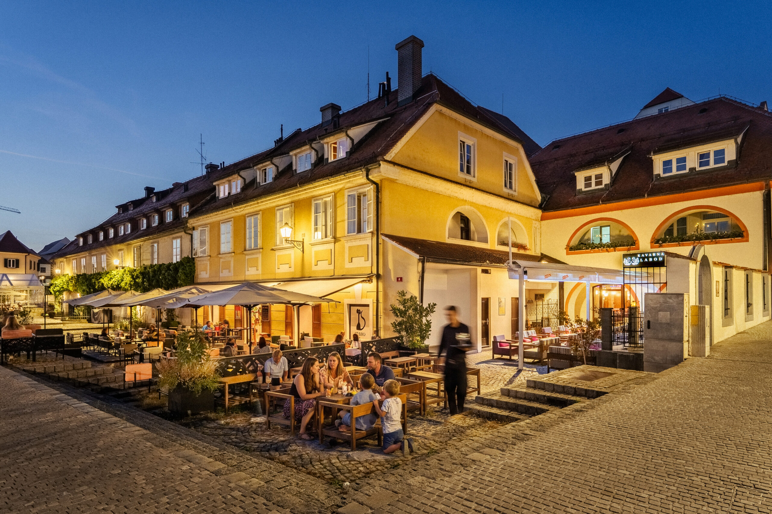 Guests dining outdoors near hotel steps at dusk