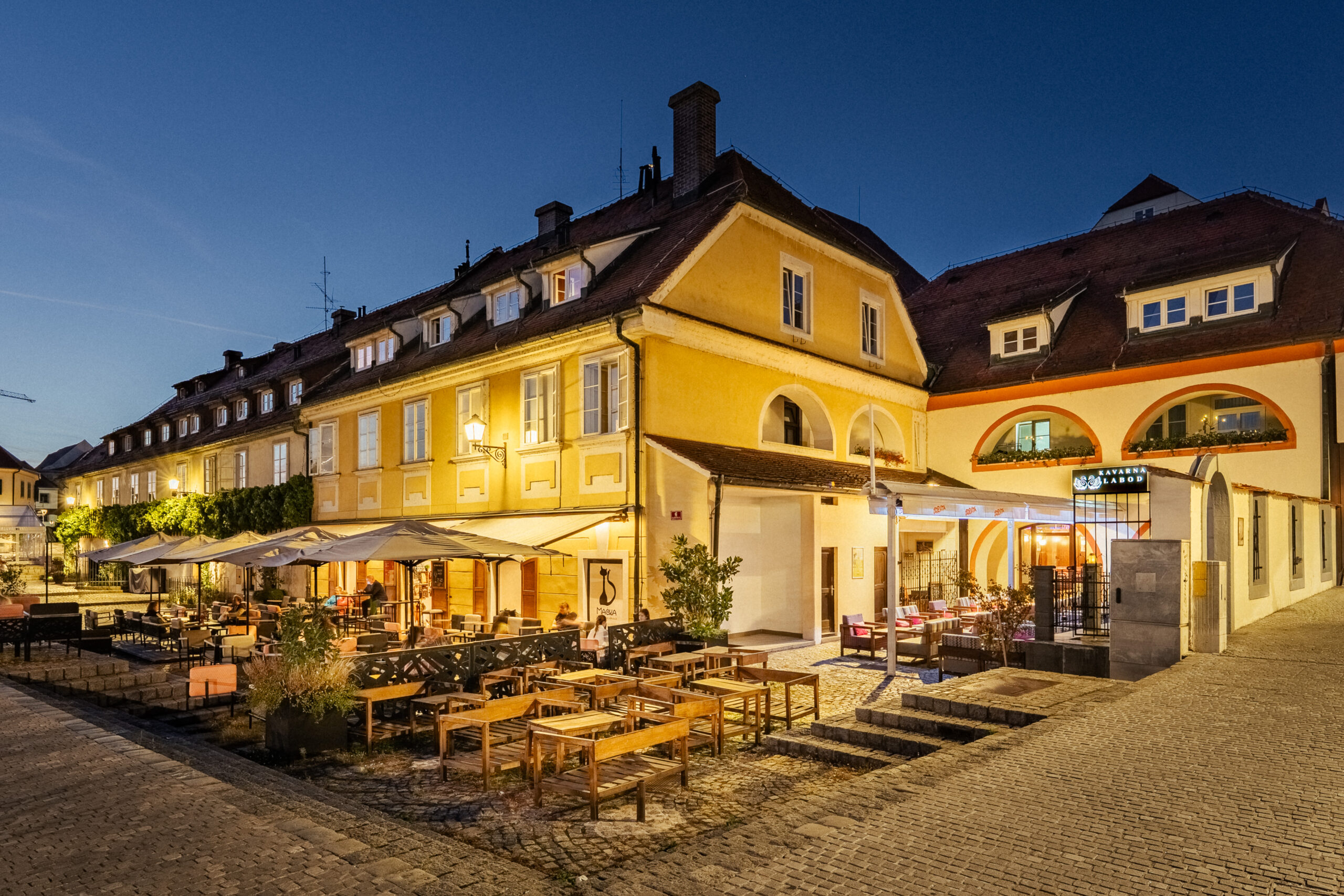 Illuminated hotel facade with outdoor seating at dusk