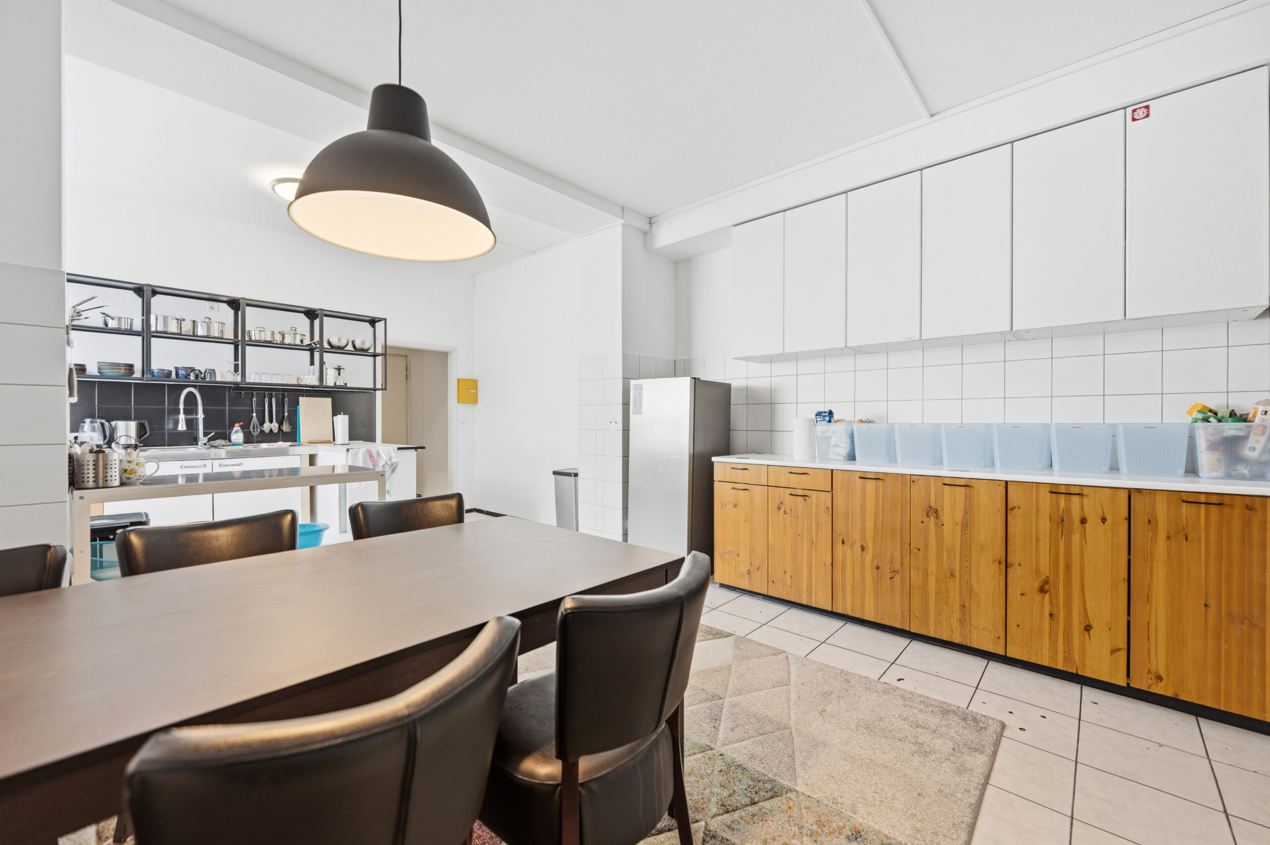 Dining area with black pendant light and wooden kitchen