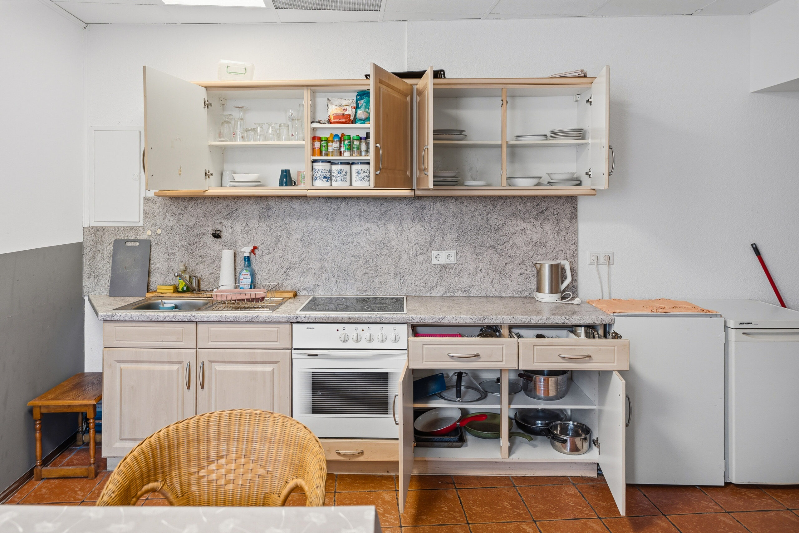 Kitchen cabinets open showing dishes and storage