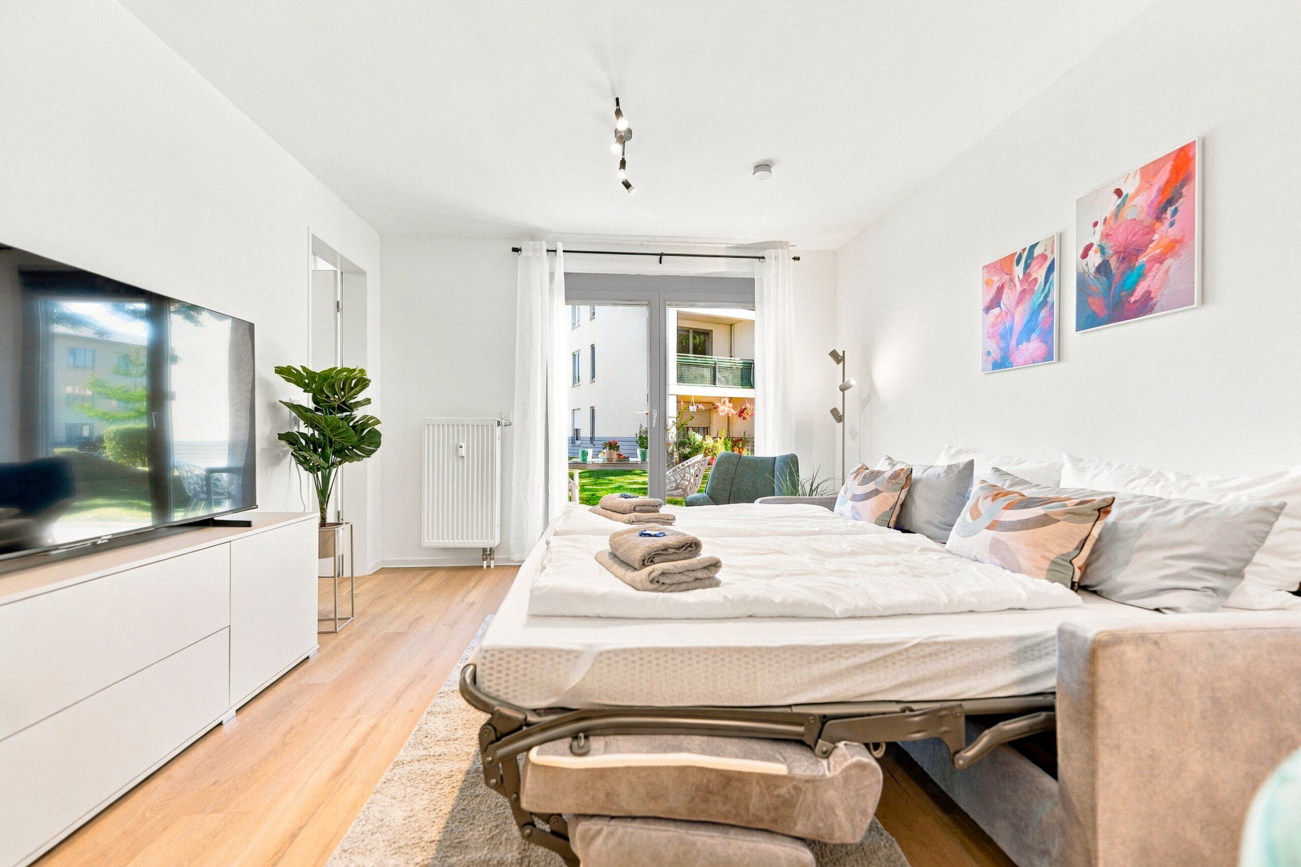 Bedroom with sofa bed facing TV and balcony